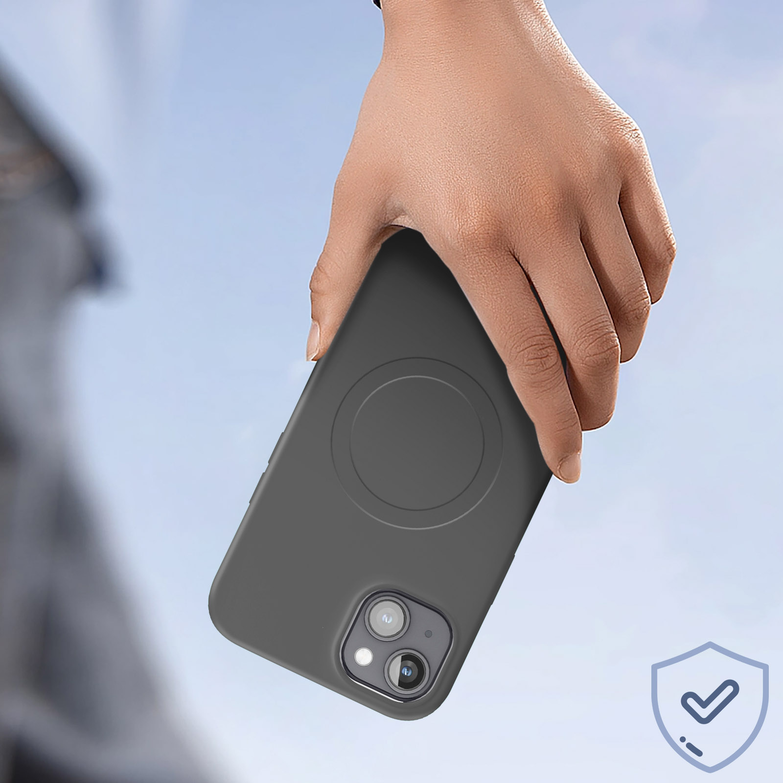 Mano che tiene una custodia grigia per telefono. Custodia grigia per telefono con anello MagSafe. Sfondo del cielo blu.