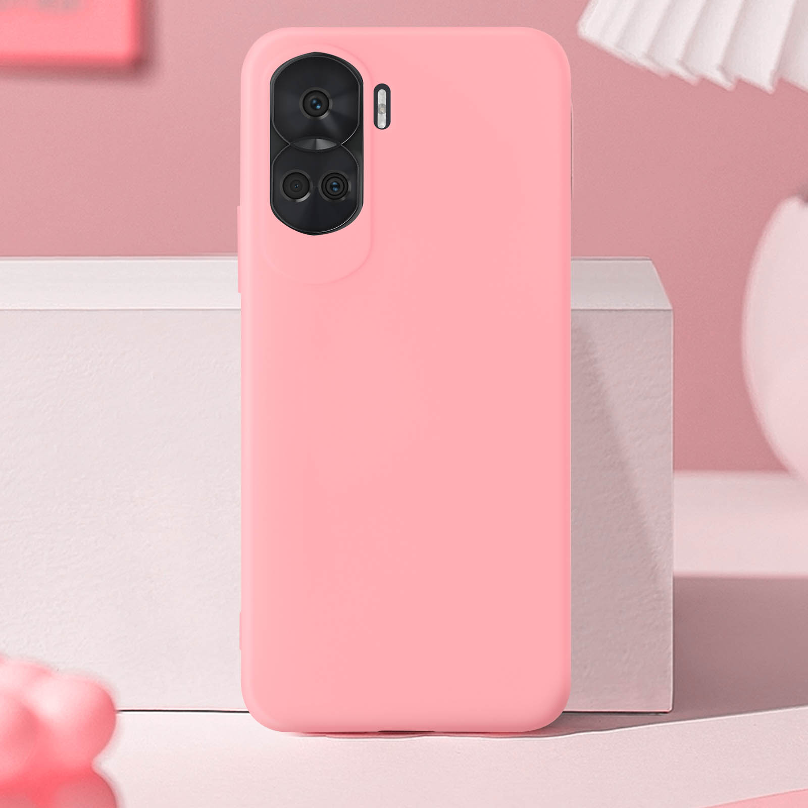 Custodia rosa per telefono, due fotocamere e flash, sfondo rosa pallido, scatola bianca, vaso sullo sfondo. Vista posteriore.