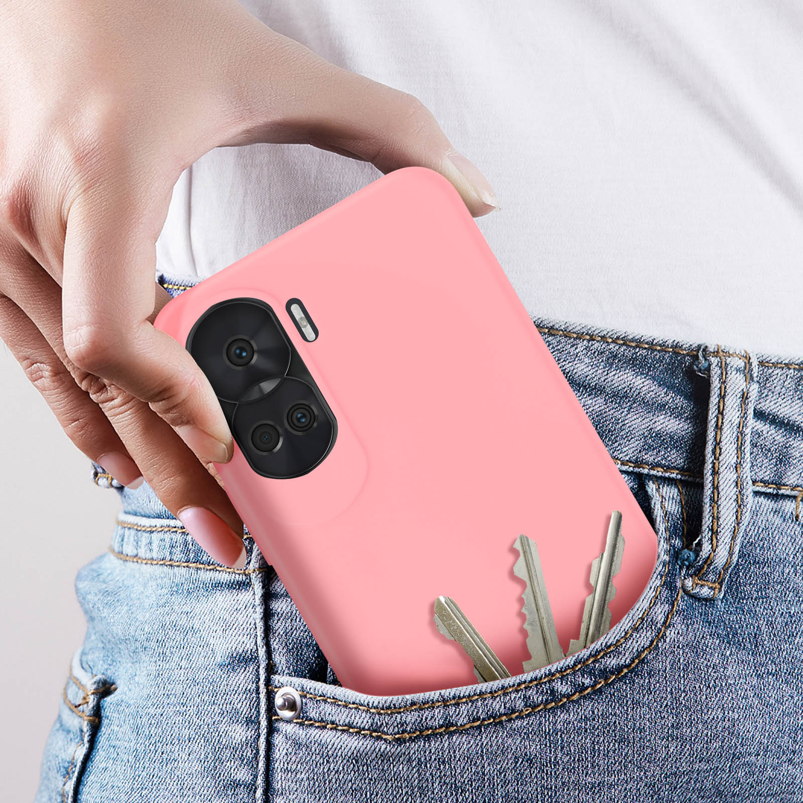 Persona che mette un telefono rosa in tasca. Sfondo jeans blu.