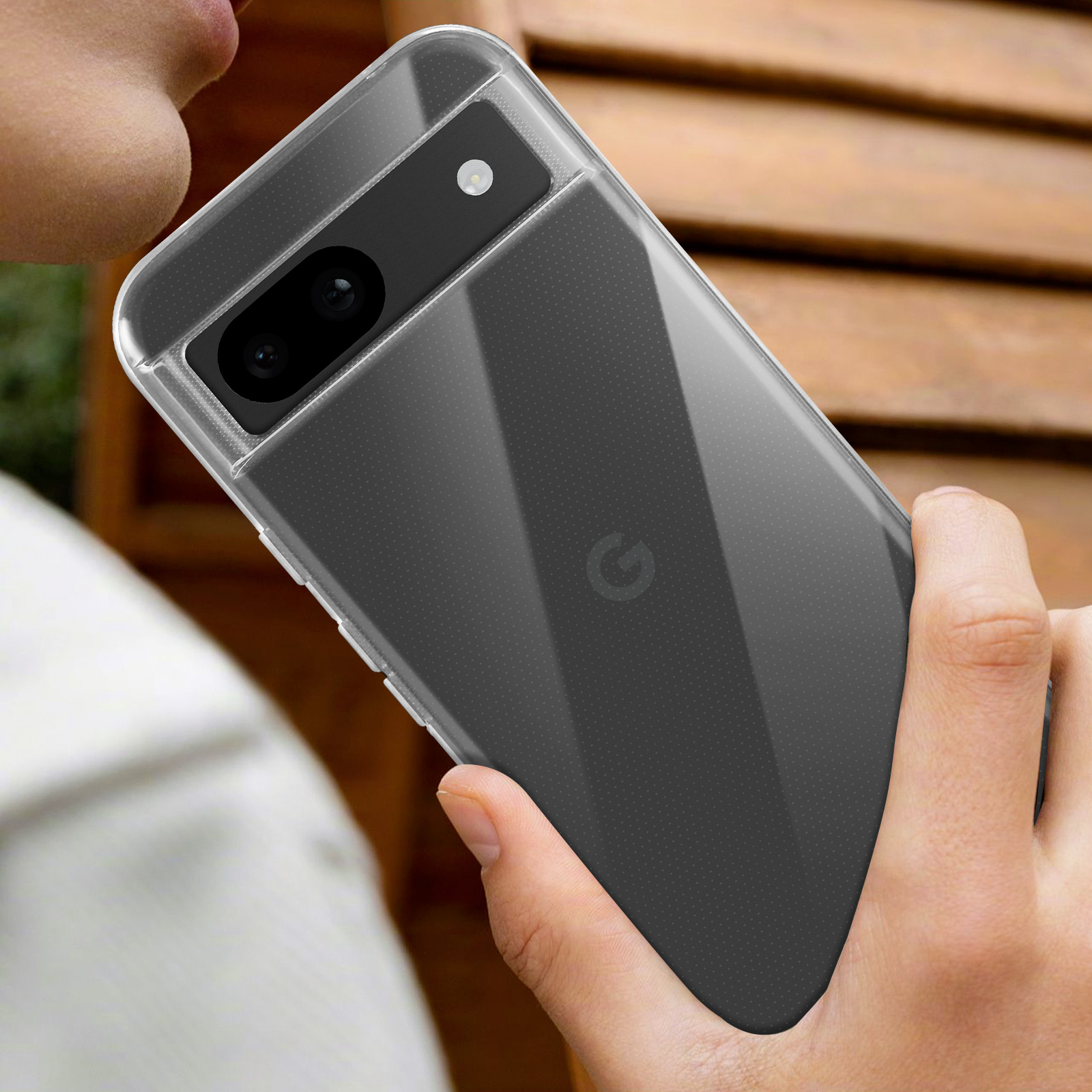 Una persona tiene in mano un telefono in una custodia. Il telefono ha una fotocamera sul retro. Una panca di legno.