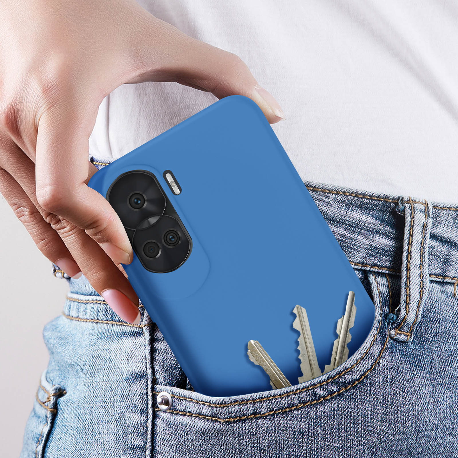 Eine blaue Handyhülle in einer Jeanstasche. Schlüssel sind in der gleichen Tasche sichtbar. Hand hält das Telefon.