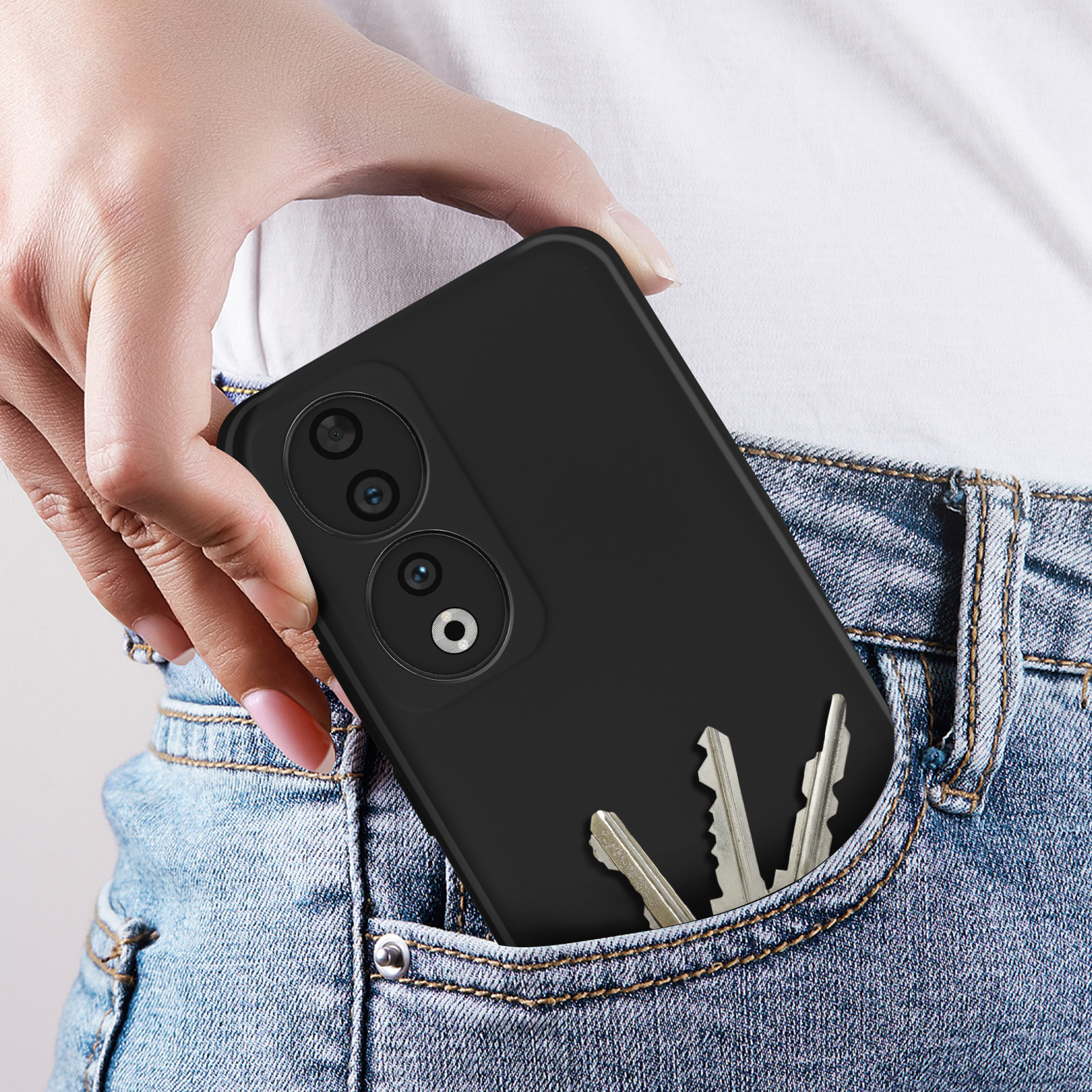 Hand die een zwarte telefoon met hoes in de zak houdt, sleutels in de zak, blauwe jeans, close-up.