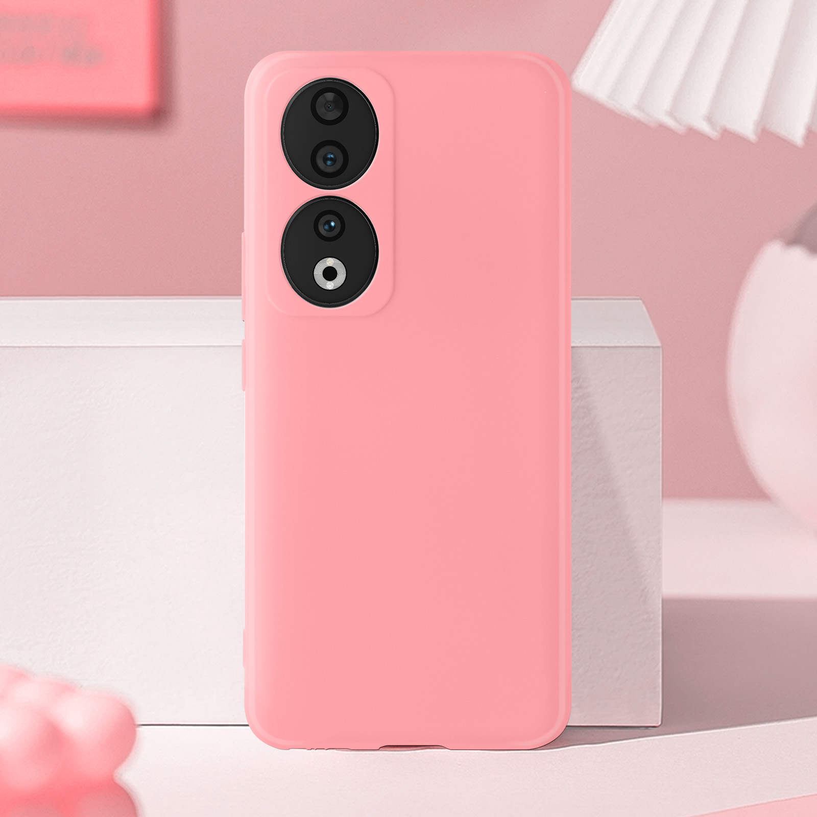 Custodia rosa con lenti della fotocamera, posta su una superficie bianca.