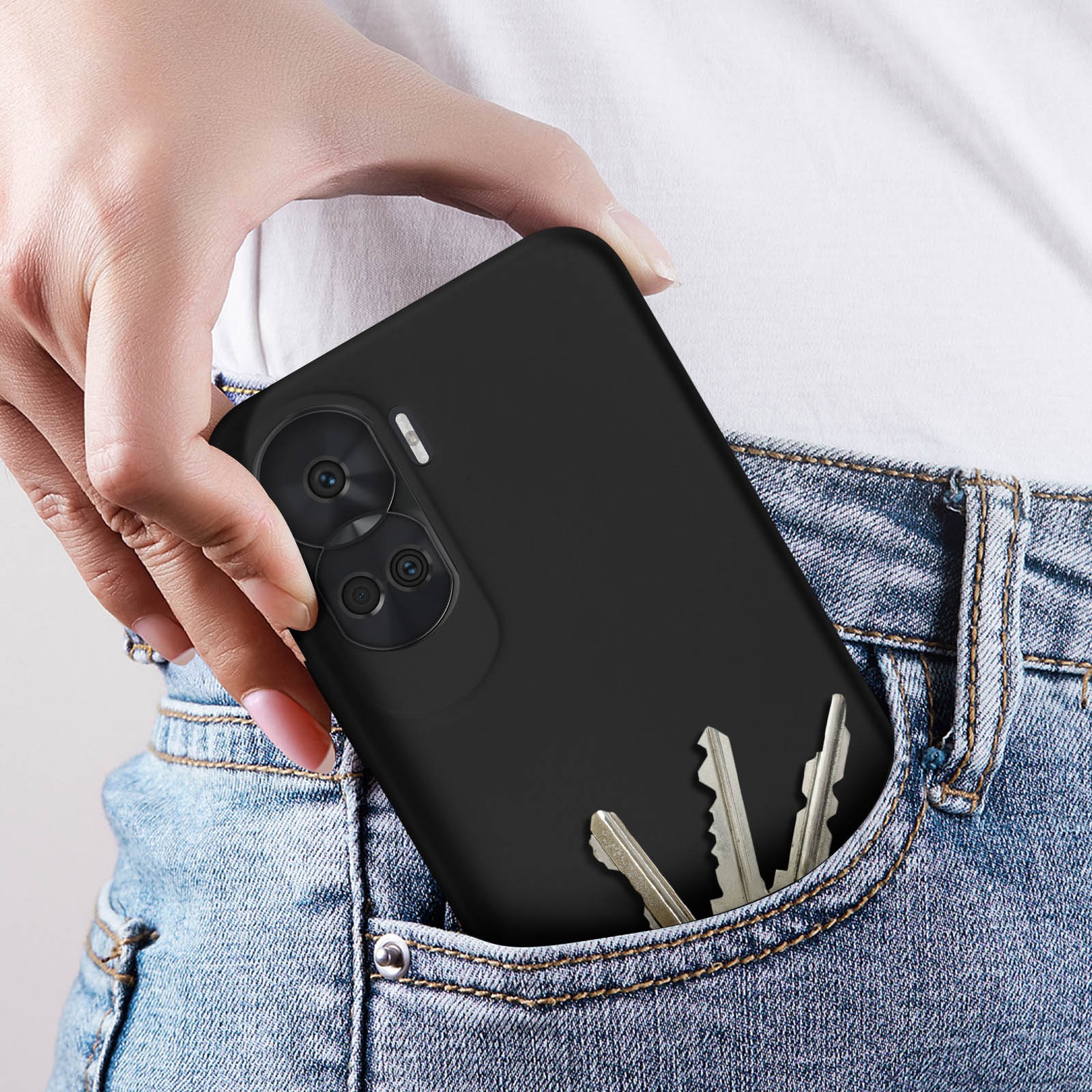 Mano con telefono nero in tasca dei jeans. Tre chiavi in tasca.