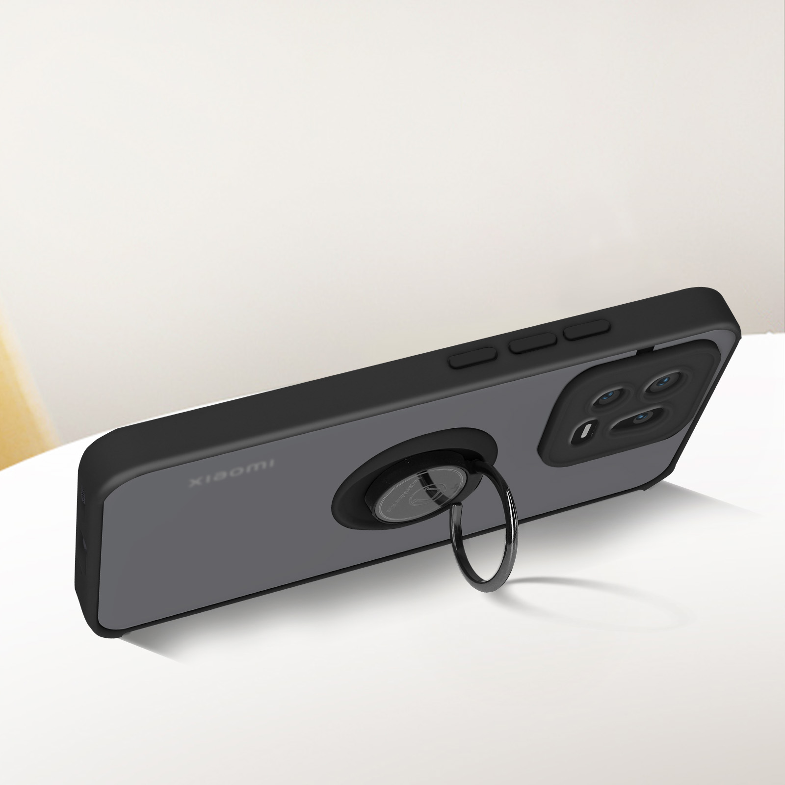 Custodia nera per telefono con porta anello. Etichetta Xiaomi. Superficie bianca.