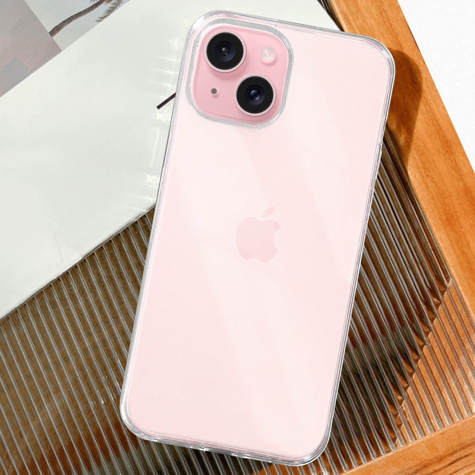Telefono rosa in custodia trasparente su vassoio di legno. Sfondo bianco. Logo Apple visibile.
