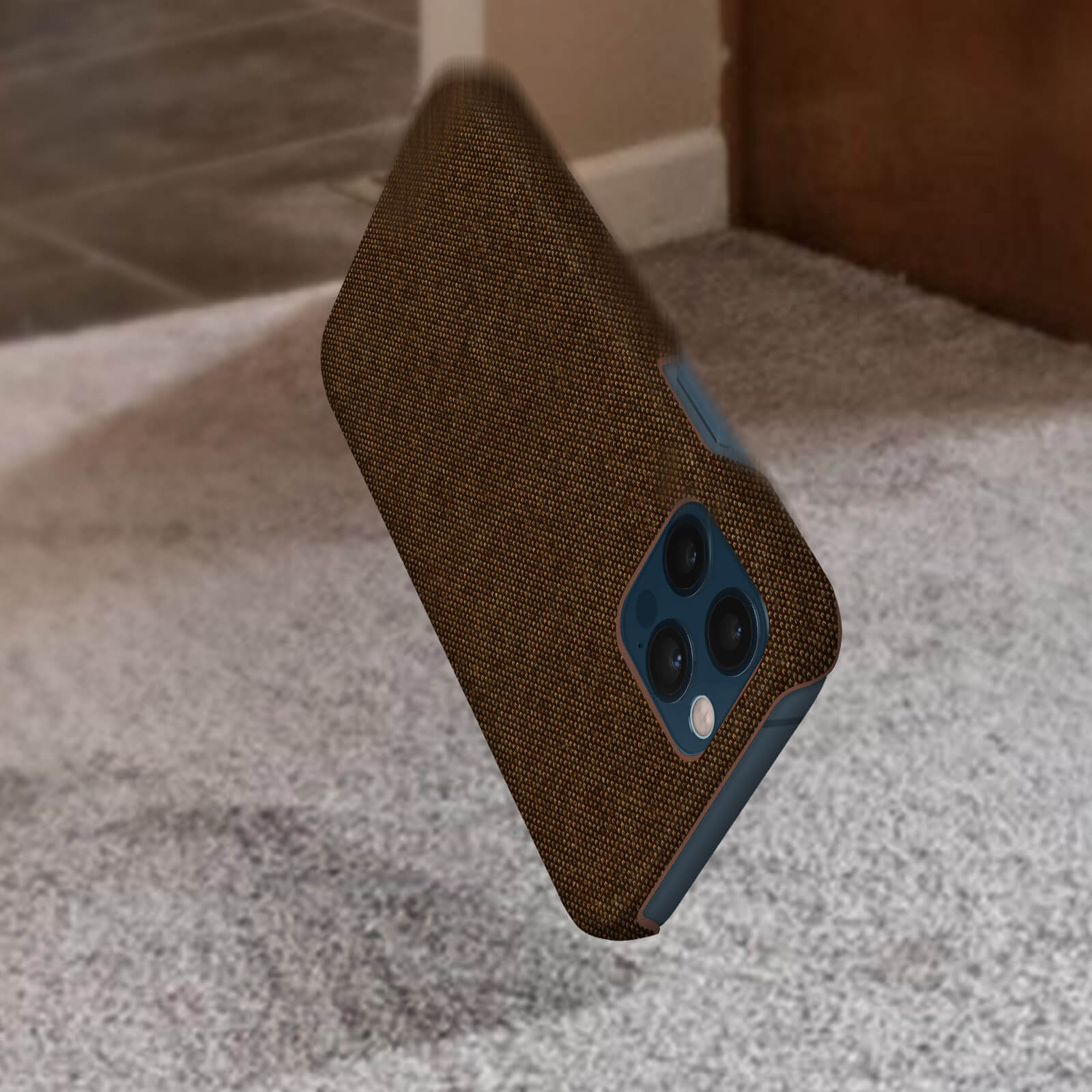 Telefono con custodia in tessuto marrone che cade. Sfondo: pavimento in moquette.