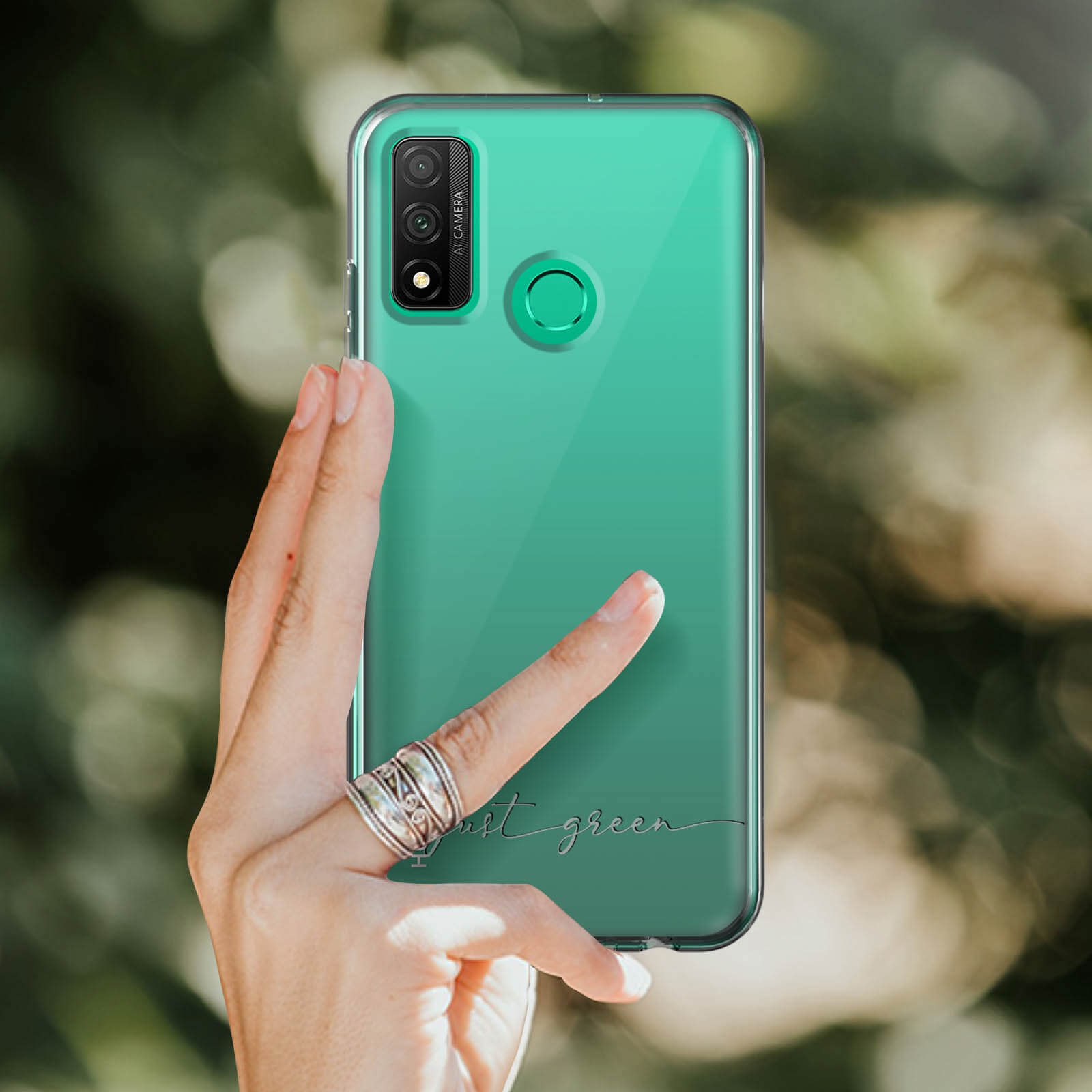 Una mano tiene una custodia trasparente con retro verde. La custodia dice 'just green' in corsivo.