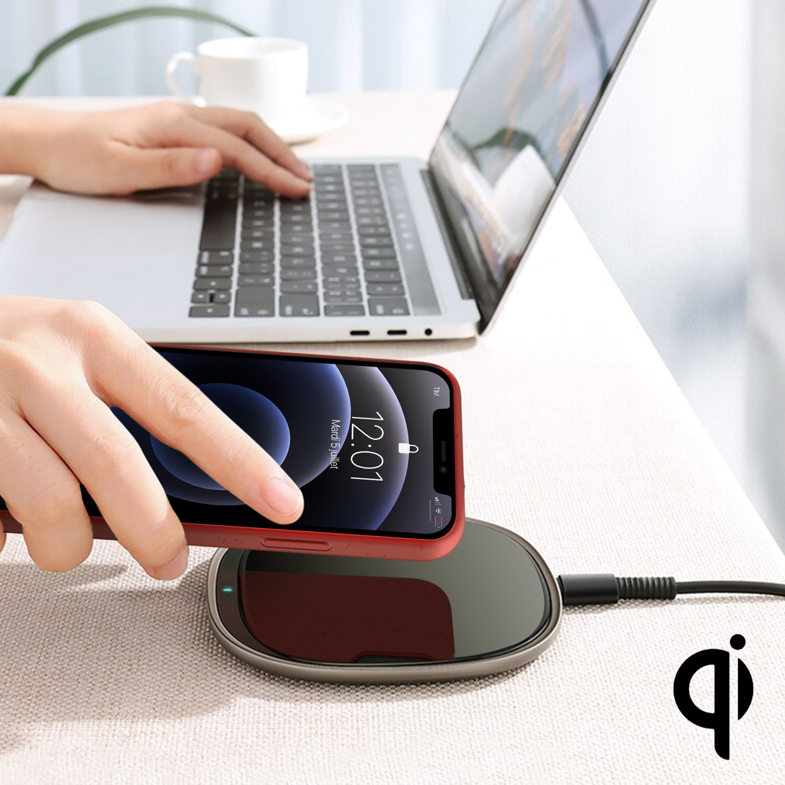 Un telefono rosso si carica su un caricatore wireless. Un laptop sullo sfondo.