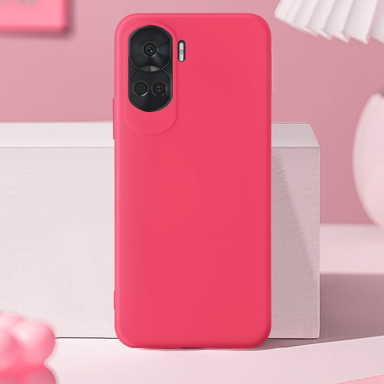 Eine pinkfarbene Handyhülle mit Kameraausschnitt. Der Hintergrund umfasst eine weiße Box und eine pinkfarbene Wand.