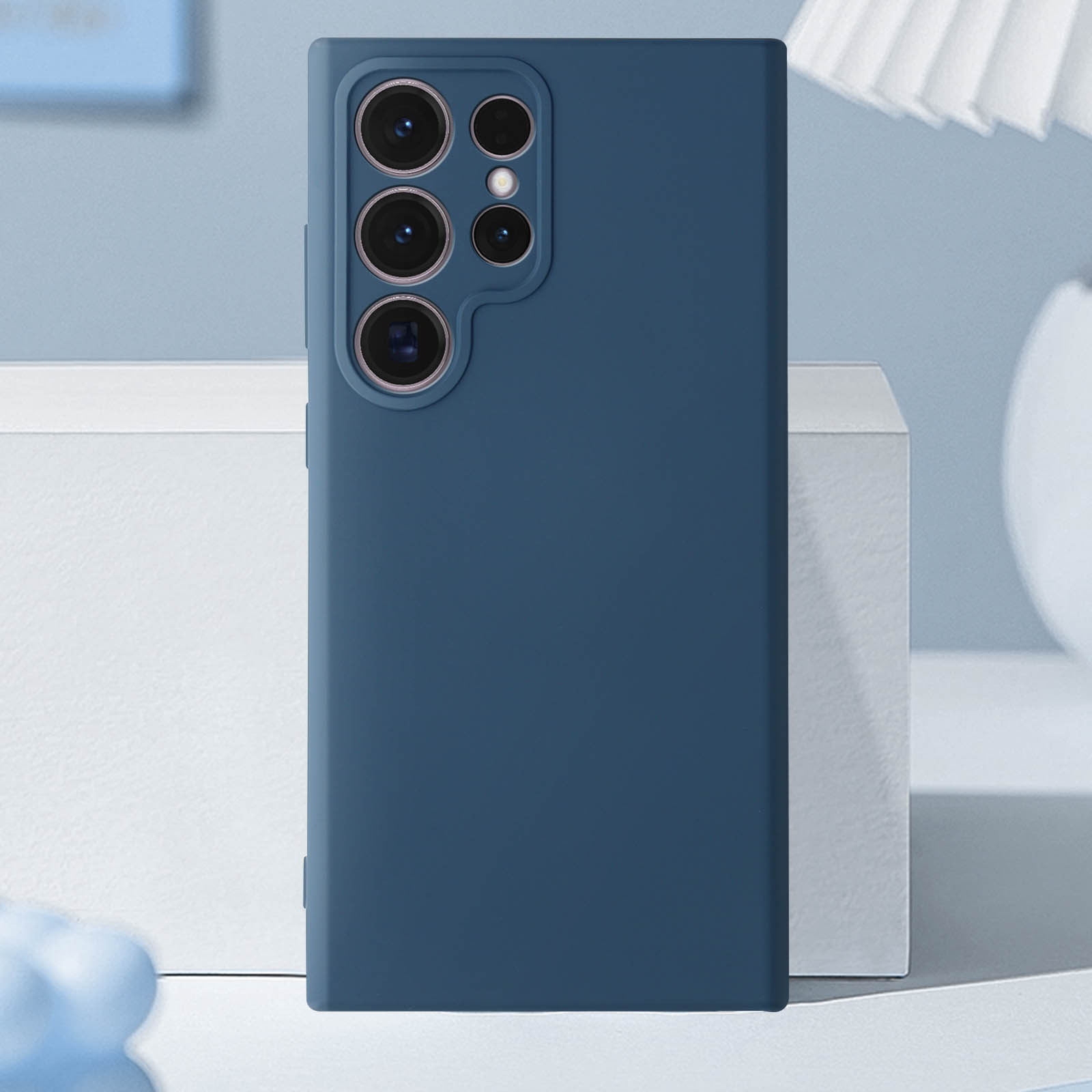 Custodia blu scuro, vista posteriore, con gruppo fotocamere rettangolare su superficie bianca.