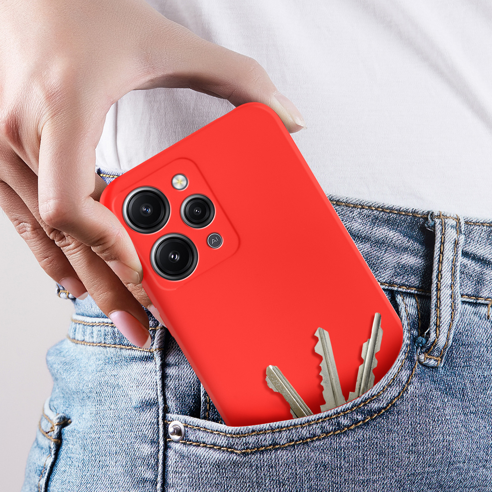 Mano che tiene un telefono rosso in tasca. Chiavi visibili. Tasca di jeans blu. Custodia rossa.