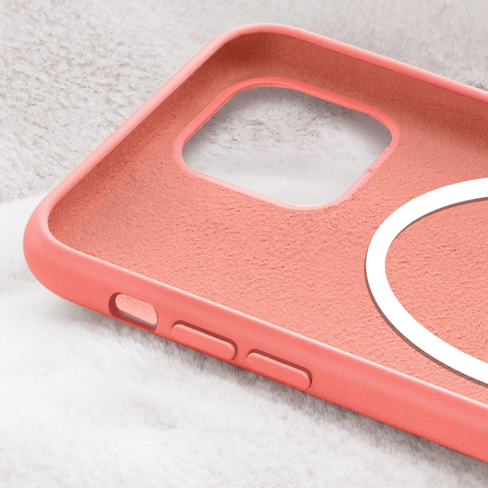 Primo piano di una custodia per telefono rosa salmone. La superficie ha una sensazione strutturata. Lo sfondo è una superficie bianca e soffice.