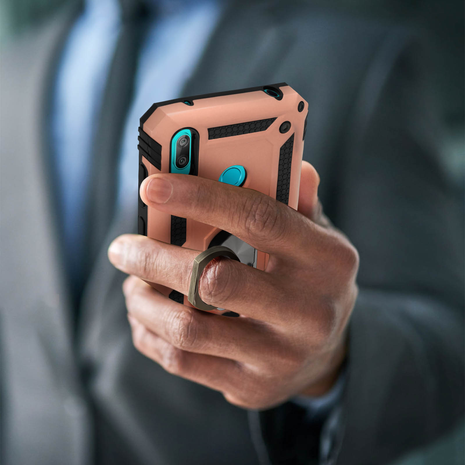 Mano che tiene un telefono con anello di supporto. La custodia è color pesca e nera.