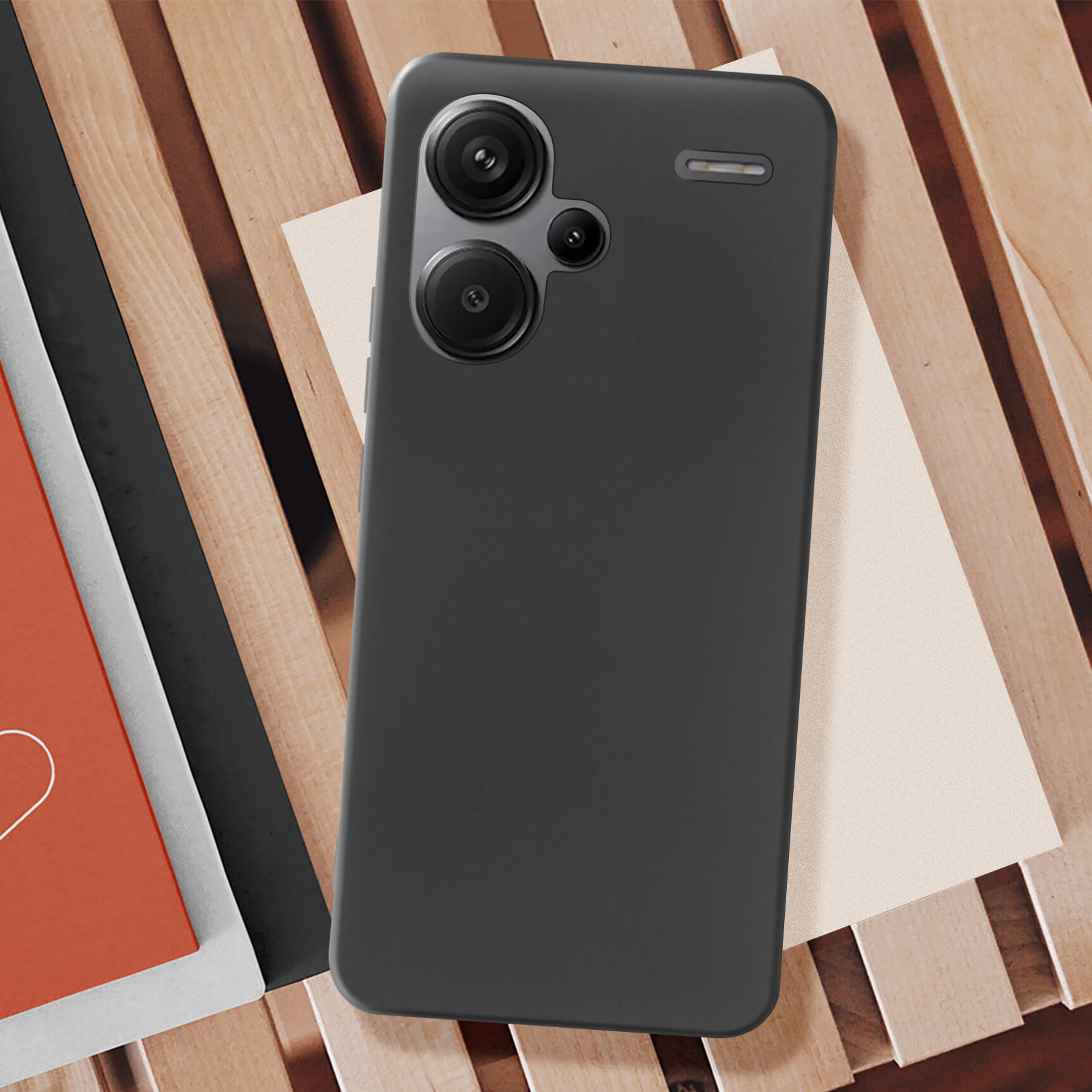 Una custodia per telefono nera con i fori della fotocamera visibili, è su una superficie di legno.