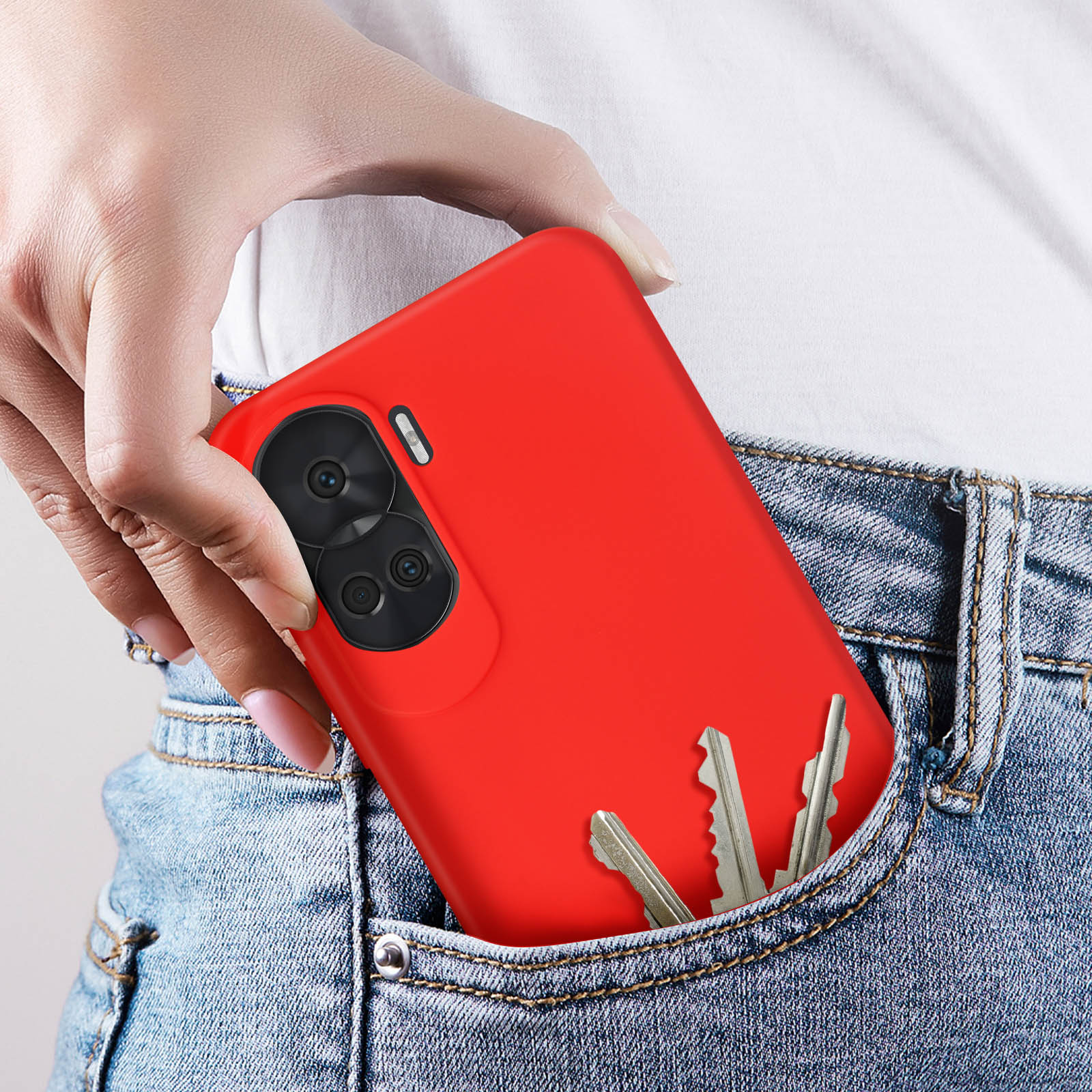 Een rood telefoonhoesje met deels zichtbare sleutels in een jeanszak. De sleutels zijn zilver.