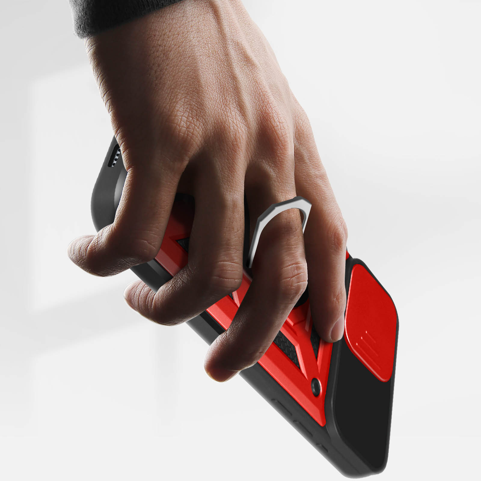 Eine Hand hält ein Telefon mit roter und schwarzer Hülle. Silberner Ring an der Hülle. Heller Hintergrund.