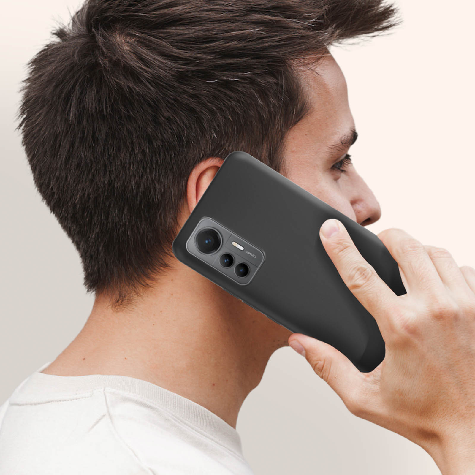 Een persoon die een zwarte telefoon vasthoudt. De telefoon zit in een zwarte hoes. De persoon draagt een wit shirt.