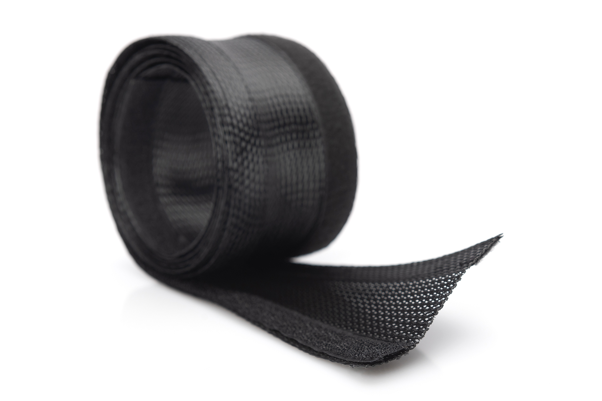 Eine schwarze Kabelumwicklung aus Netzgewebe, aufgerollt auf einer weißen Oberfläche.