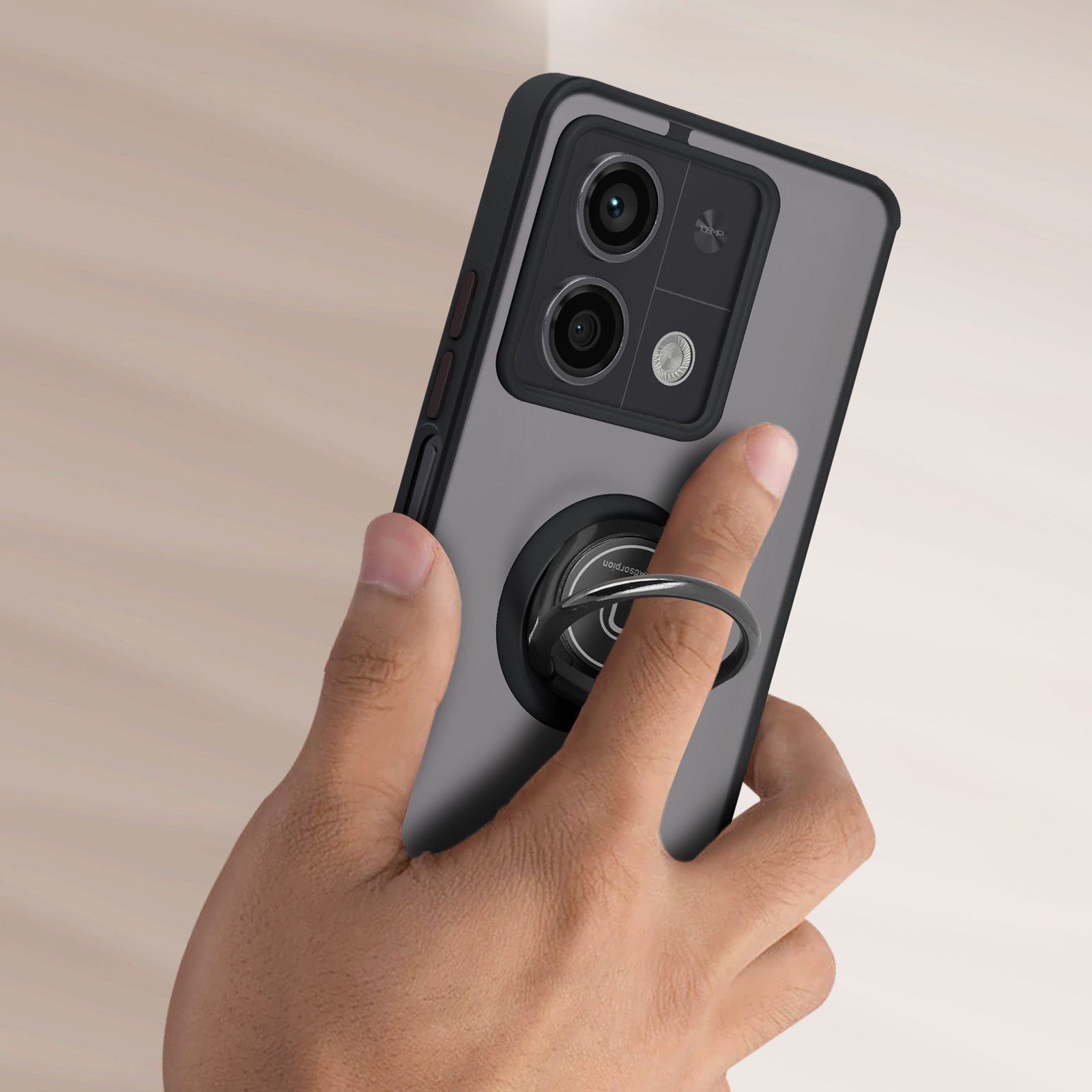 Mano che tiene un telefono con un anello di supporto. Il telefono ha una custodia nera e grigia. Sfondo in legno.