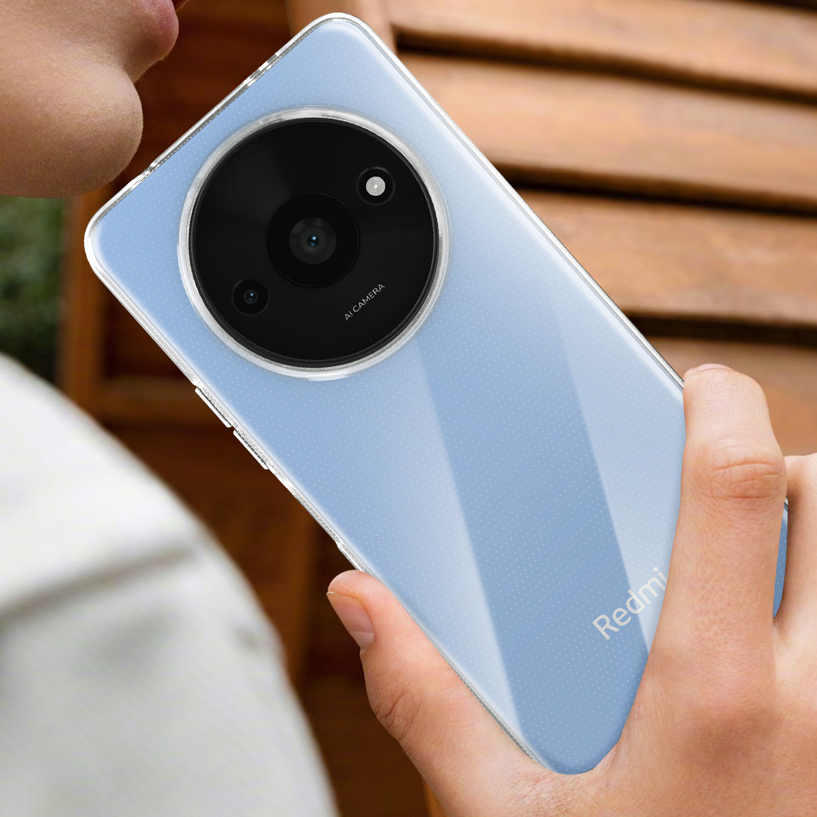 Una persona tiene in mano un telefono azzurro con un grande rigonfiamento della fotocamera e una custodia trasparente.