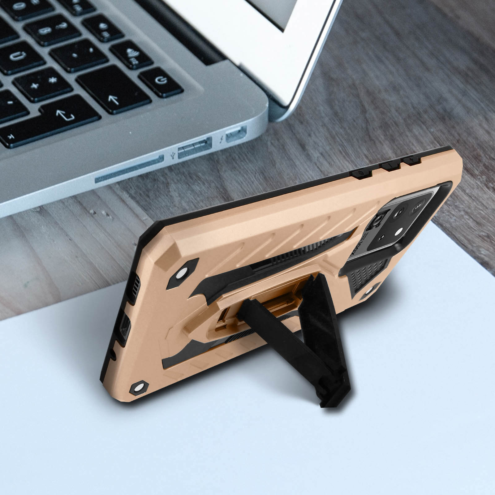 Una custodia per telefono su una scrivania con un laptop. La custodia è beige e nera, con cavalletto.