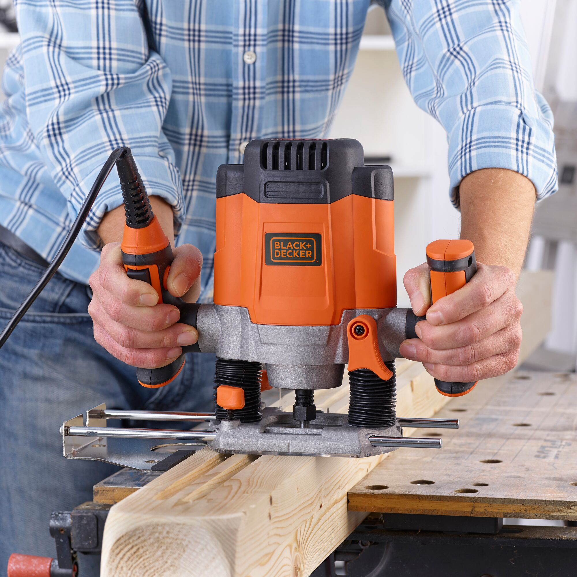 Hombre usando una fresadora Black+Decker negra y naranja. Trabajando en una tabla de madera.