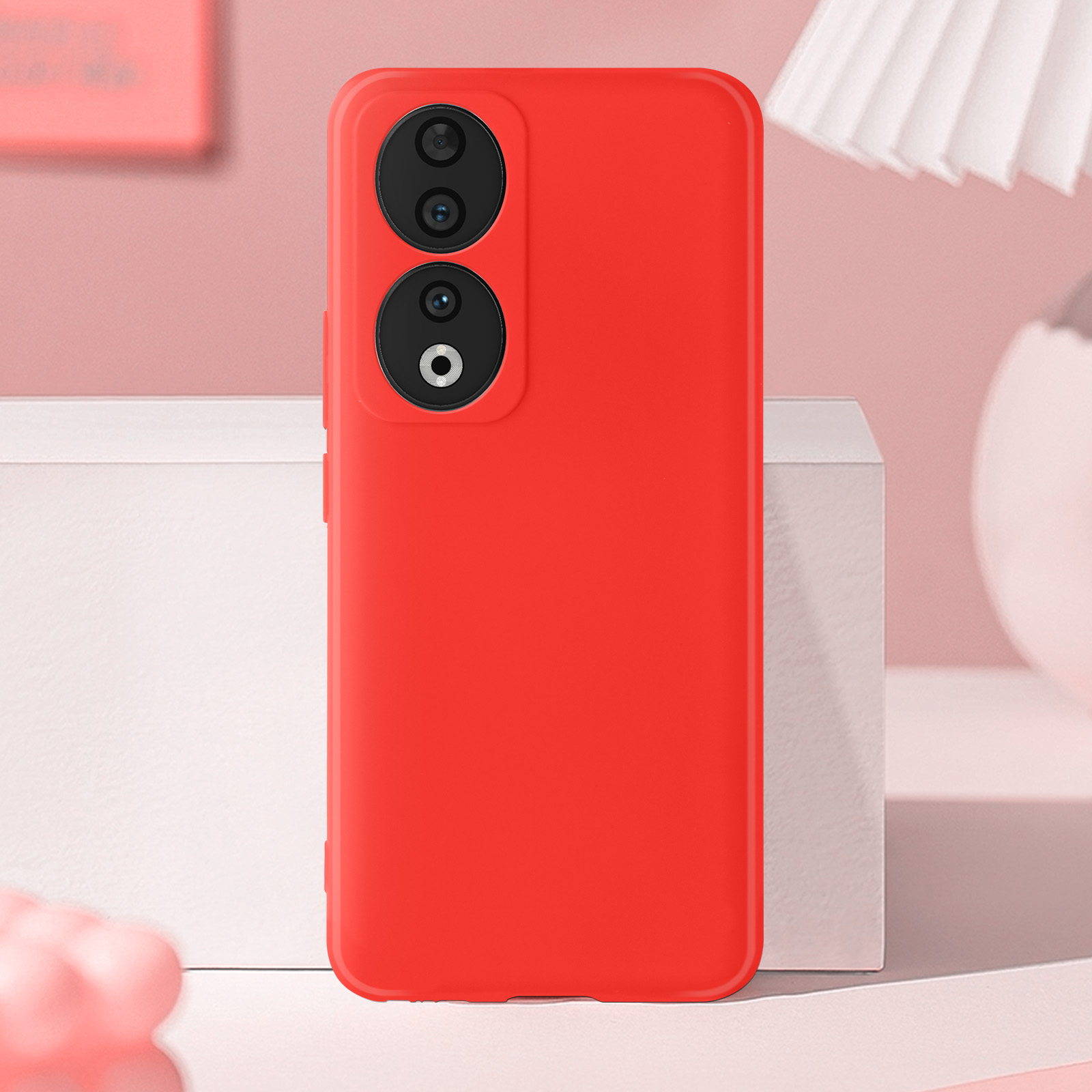 Custodia rossa per telefono con due obiettivi della fotocamera. Lo sfondo è rosa chiaro e bianco.