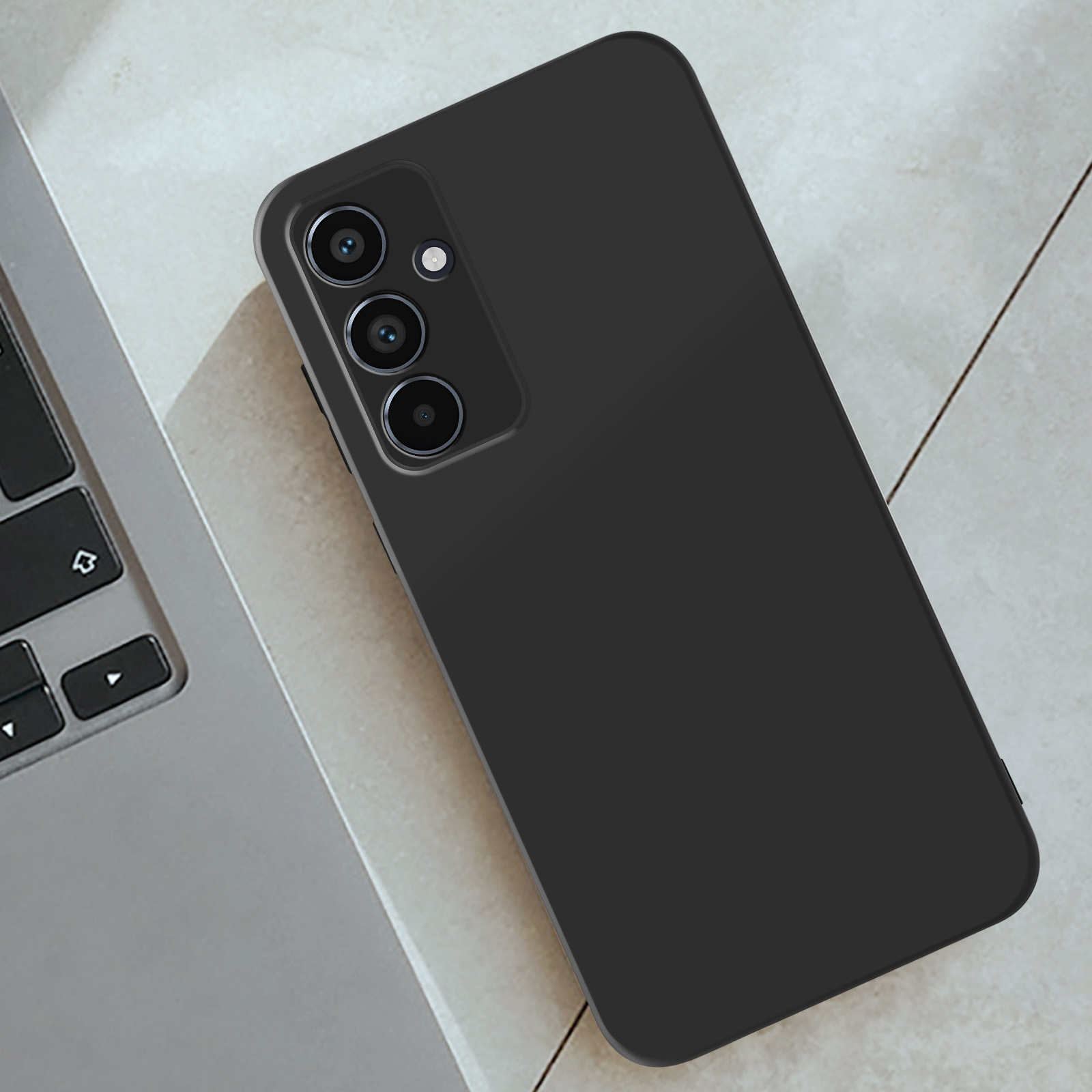 Custodia nera per telefono su un laptop. Il telefono ha una configurazione a tripla fotocamera, su una superficie chiara.