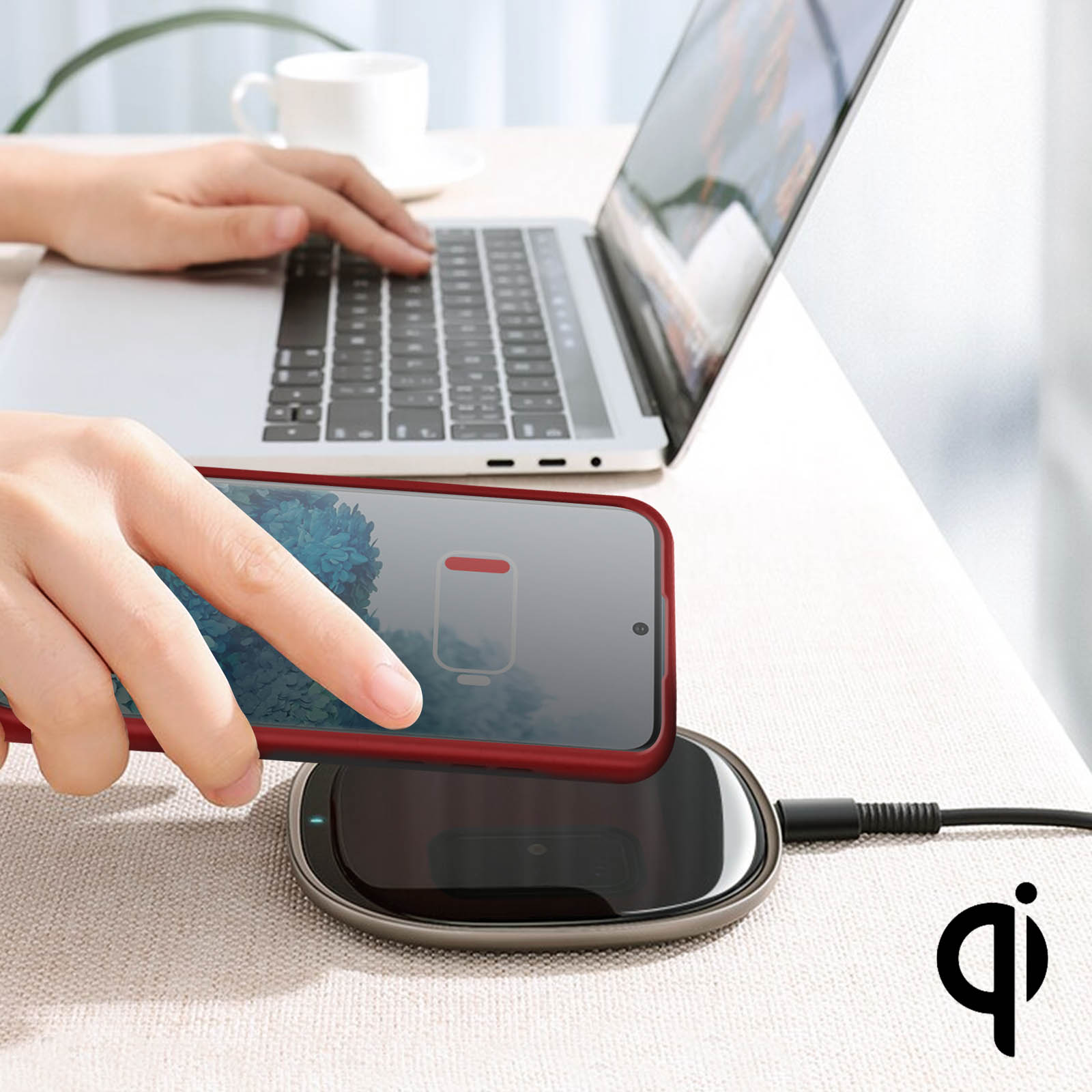 Telefono in carica wireless. Laptop aperto sullo sfondo.