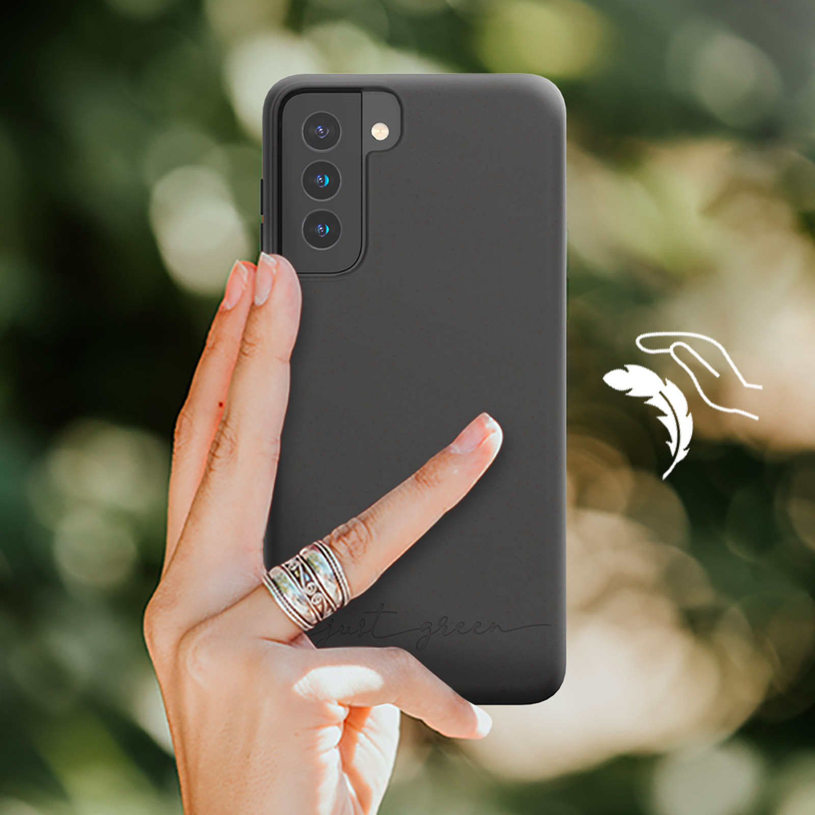 Una mano che tiene un telefono con una custodia nera, le parole 'just green' sono visibili.