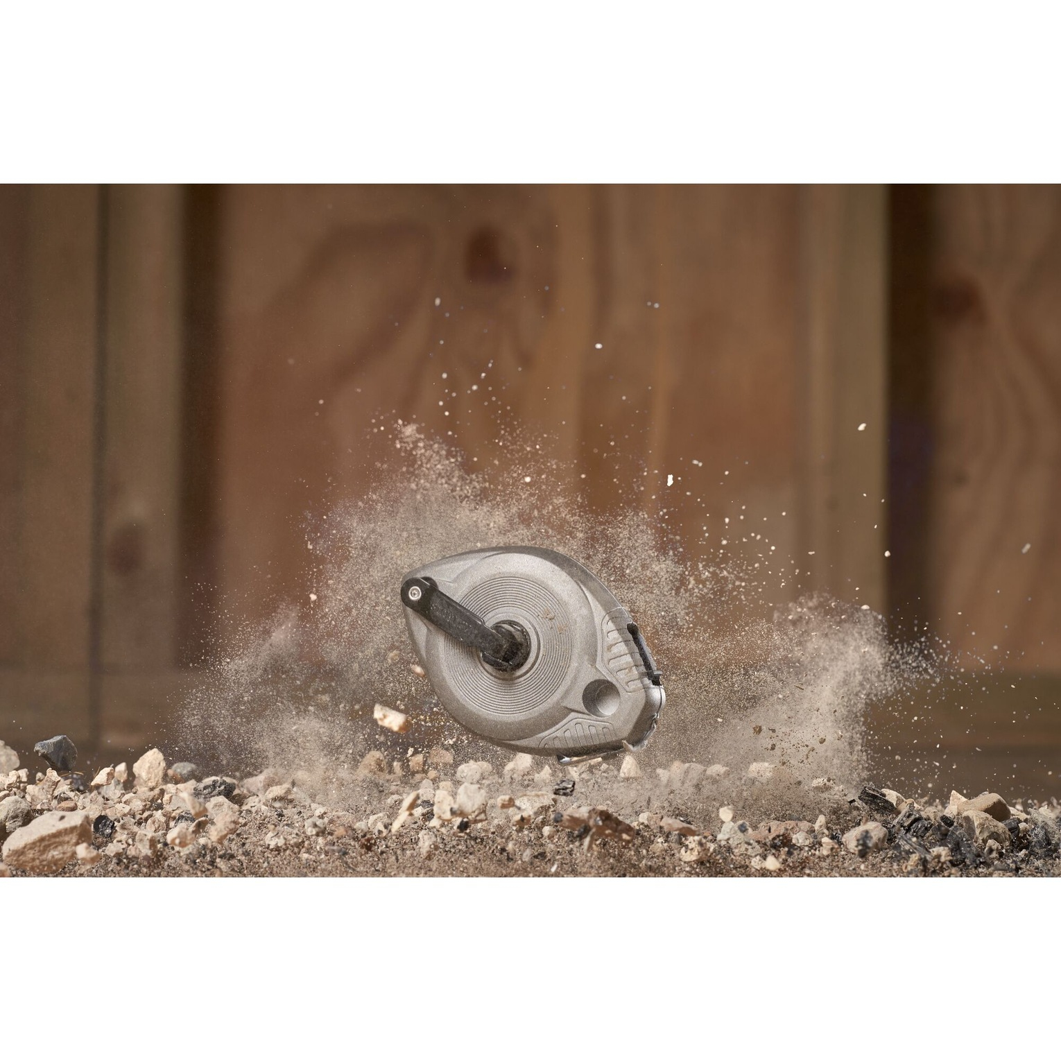 Szara szpula do linii kredowej w powietrzu, z cząsteczkami pyłu wokół.