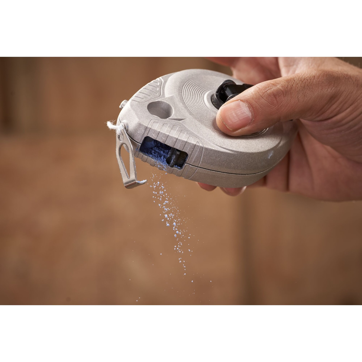 Ręka trzymająca szarą linię kredową, pokazująca wypadający proszek kredowy.