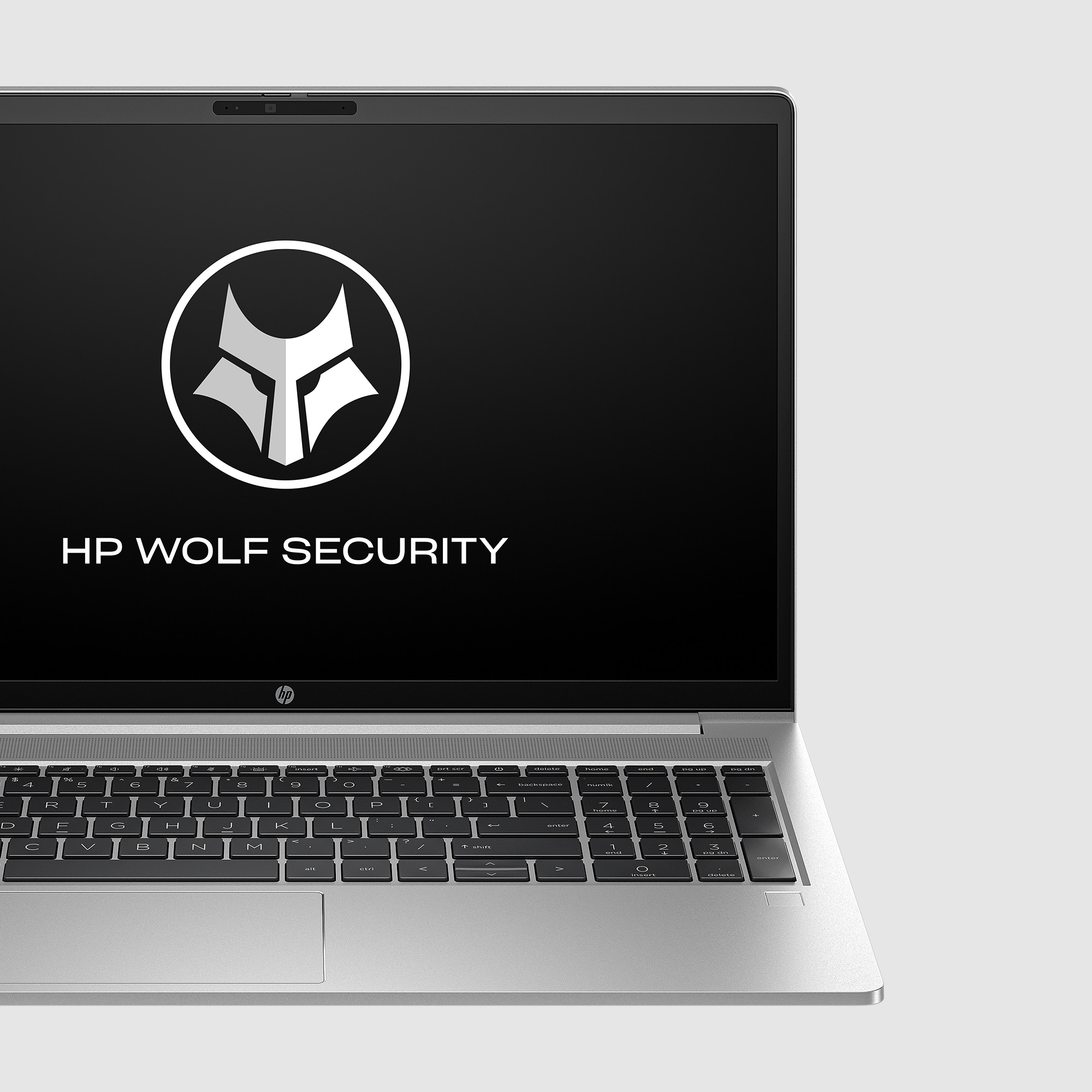 Laptop z logo HP Wolf Security na ekranie, na jasnoszarej powierzchni.
