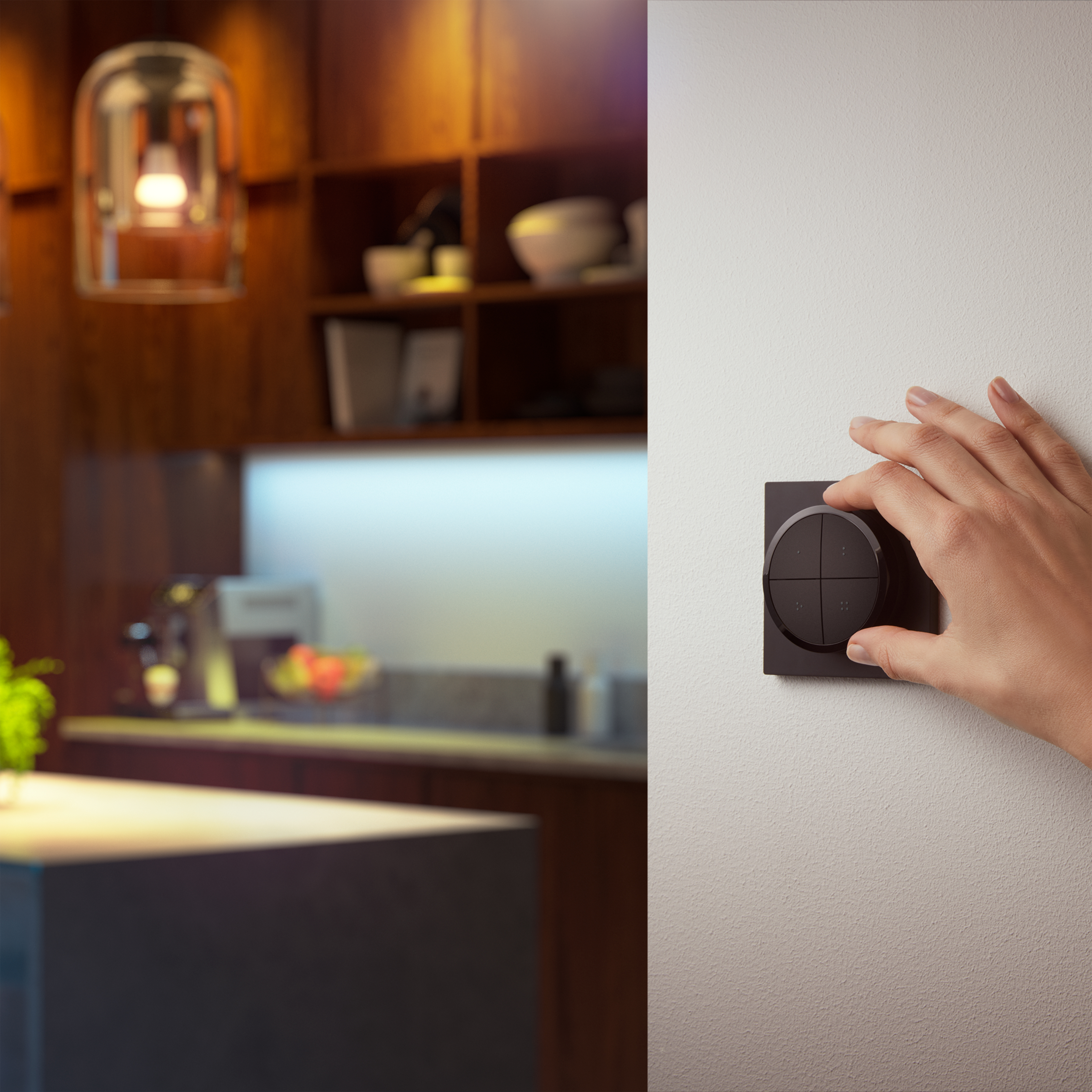 Dłoń obracająca czarny inteligentny włącznik światła na ścianie, wnętrze kuchni w tle.