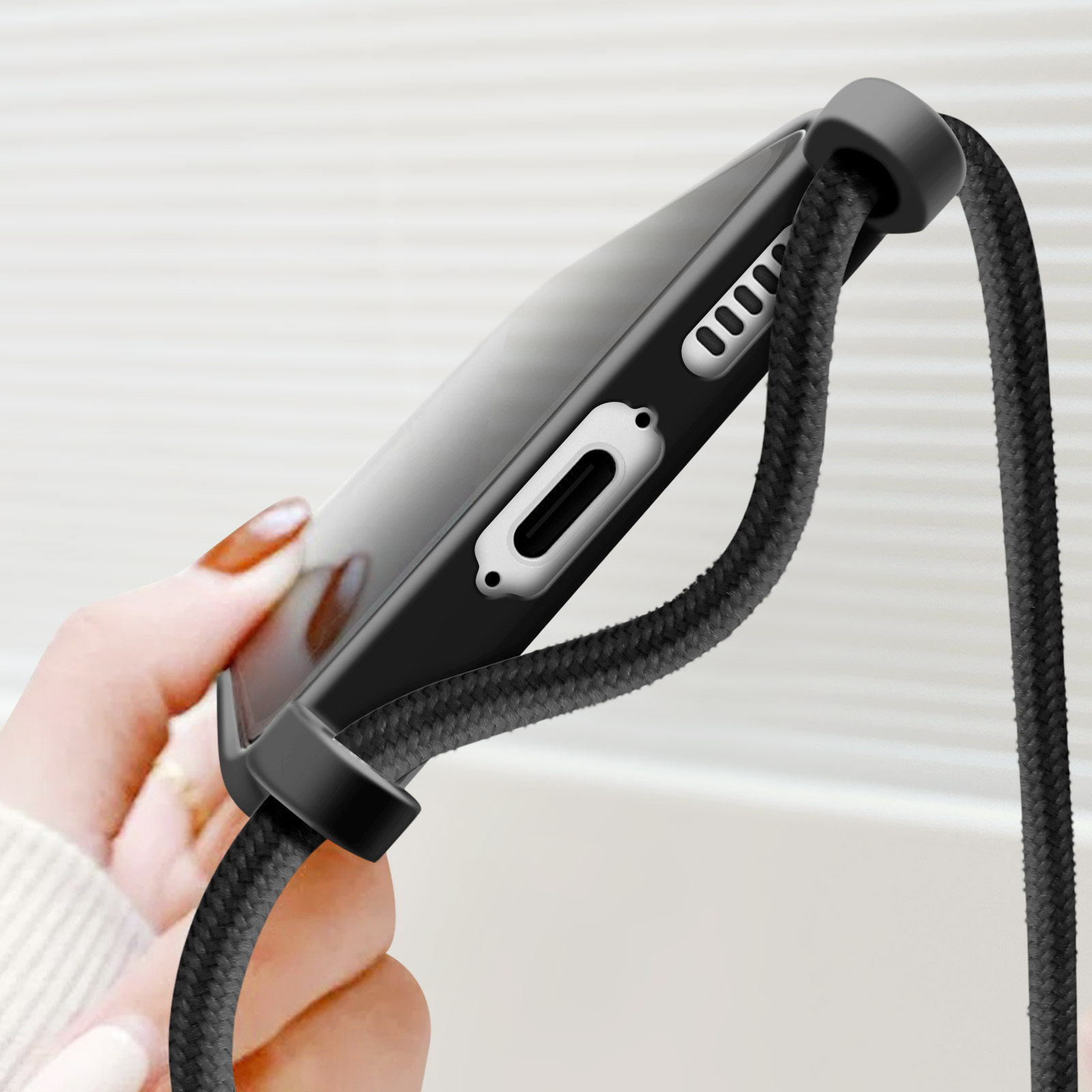 Coque noire avec cordon noir, une main tenant le téléphone.