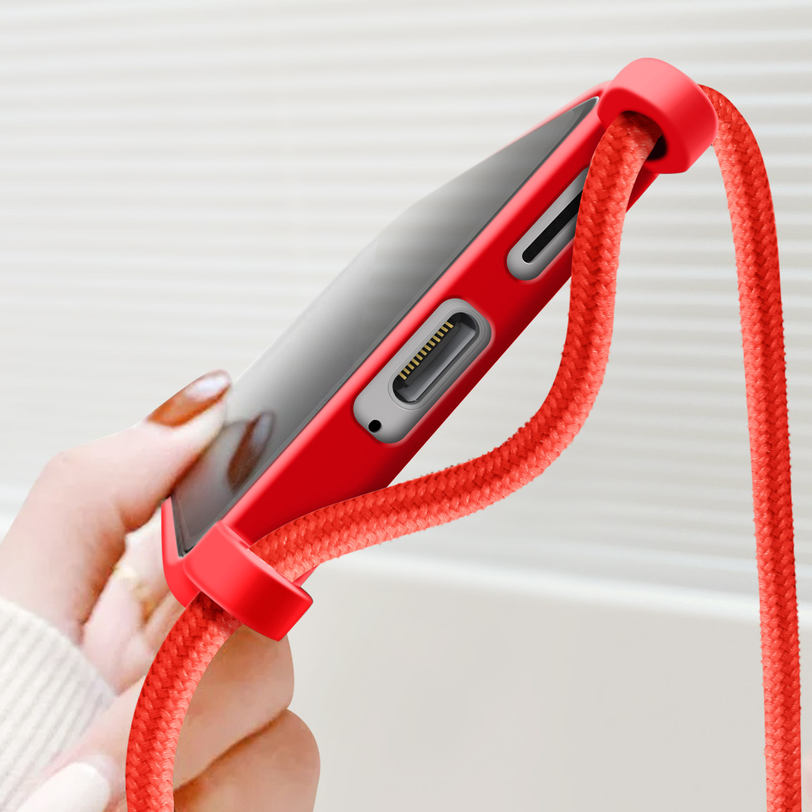 Een telefoonhoesje met een rode riem. De telefoon wordt door een persoon vastgehouden.