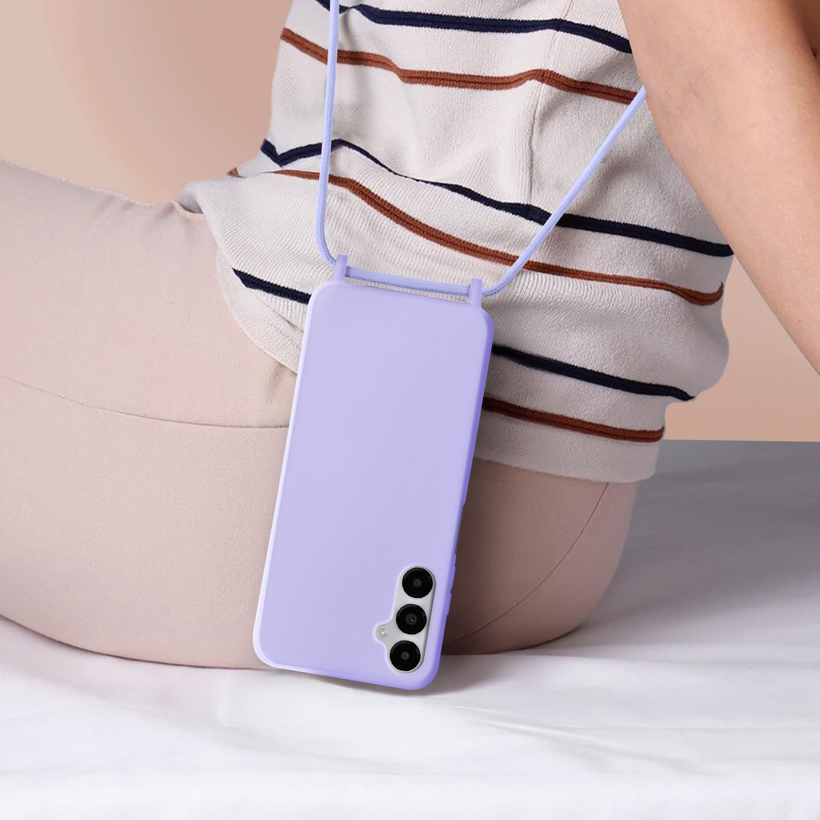 Een persoon zit met een paarse telefoon en een koord om de nek. De achtergrond is licht.