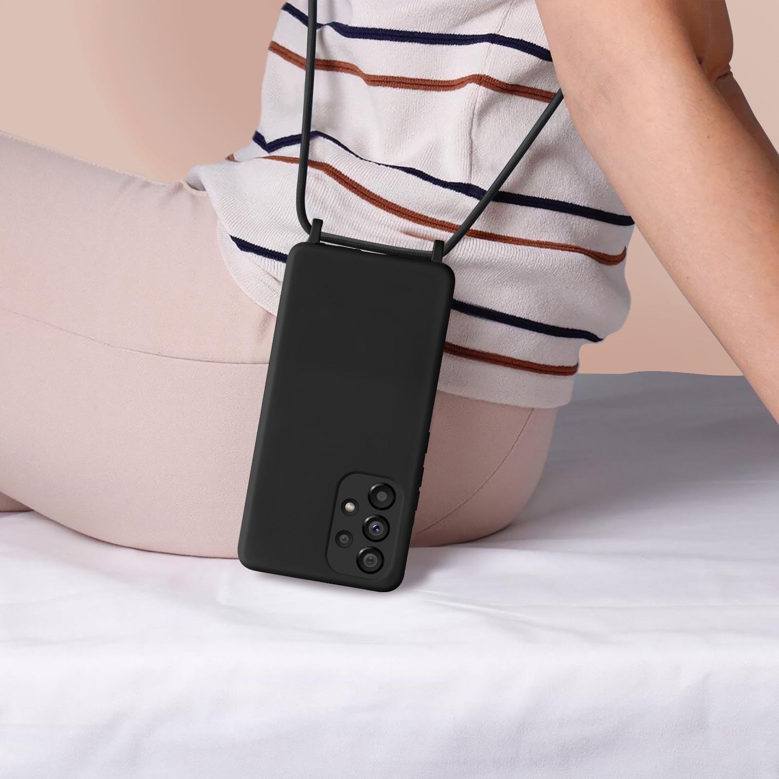 Une personne portant une coque de téléphone noire avec une lanière noire. Le téléphone est dans une poche.