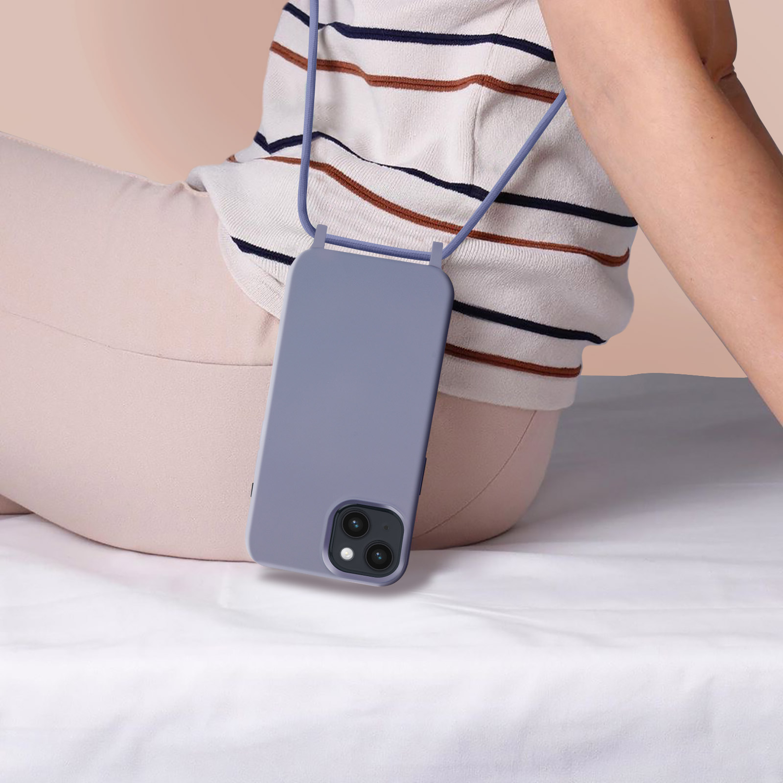 Persoon die een paarse telefoon met een bandje vasthoudt. De persoon zit op een wit oppervlak.