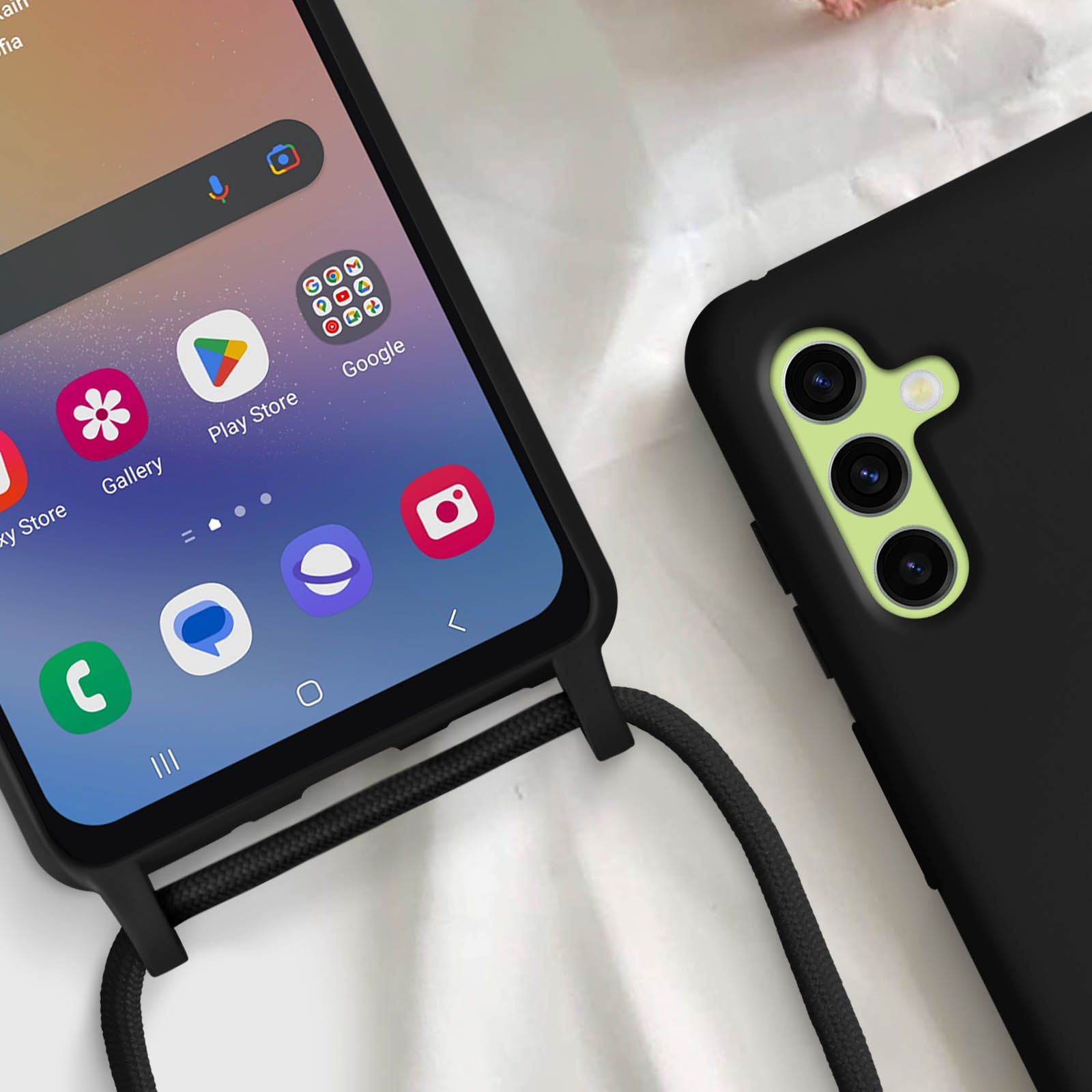 Due telefoni: uno nero con app, l'altro nero con design fotocamera verde. Custodia nera con corda.