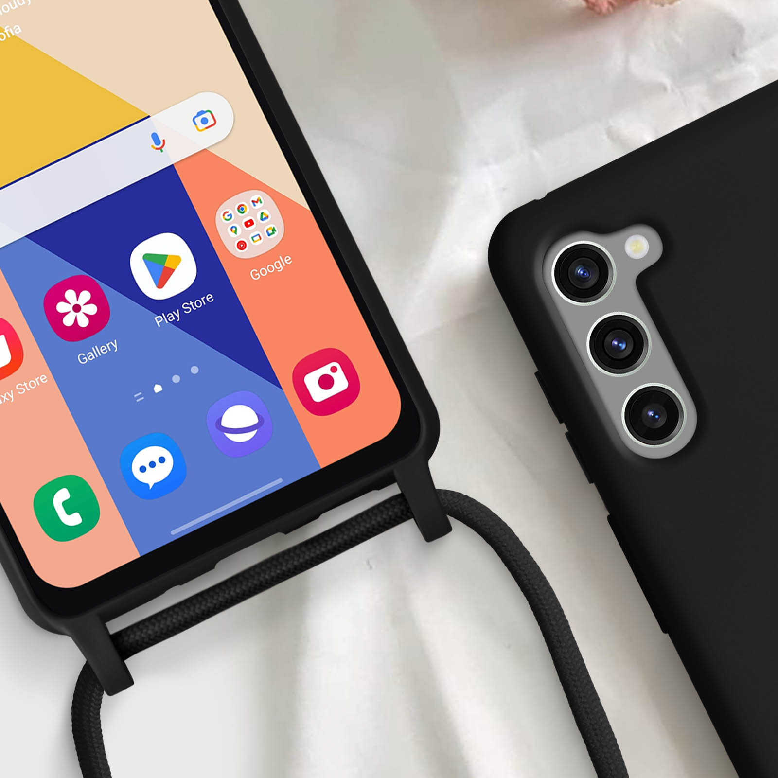 Telefono nero con schermo acceso e custodia nera con cinturino. Lo schermo mostra icone.