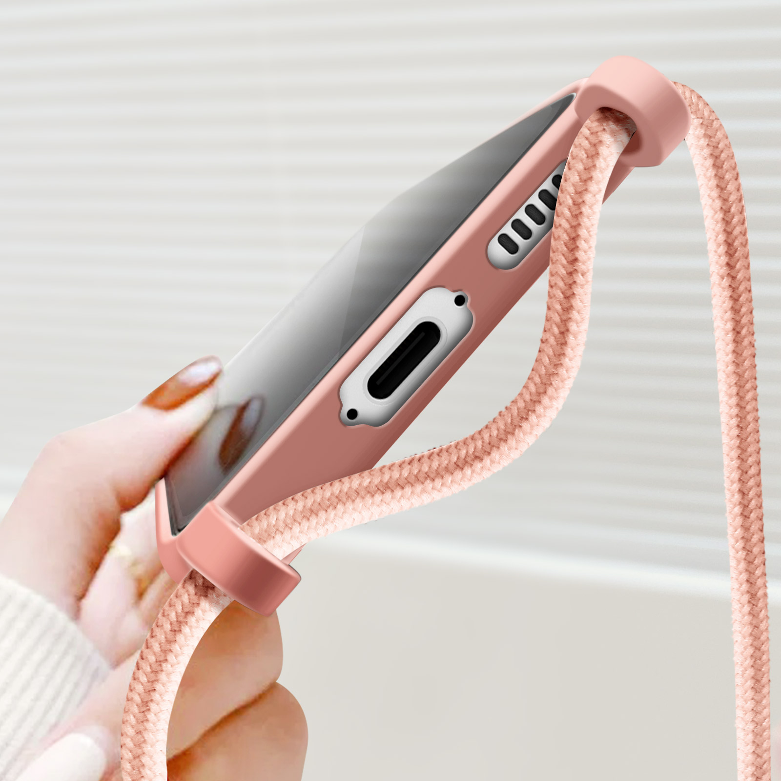 Coque de téléphone rose avec cordon rose attaché. Main tenant le téléphone. Fond blanc.