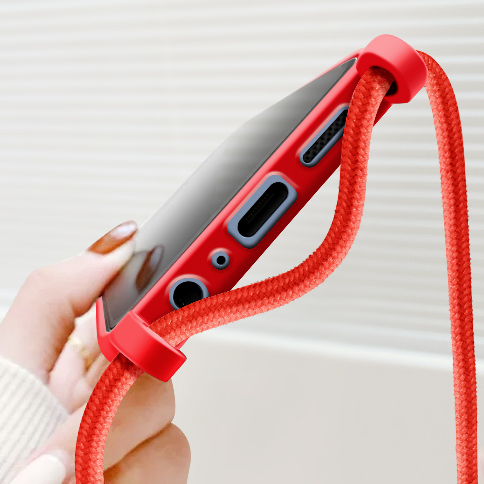 Custodia rossa per telefono e cordino rosso, tenuti da una mano. La custodia mostra uno schermo.