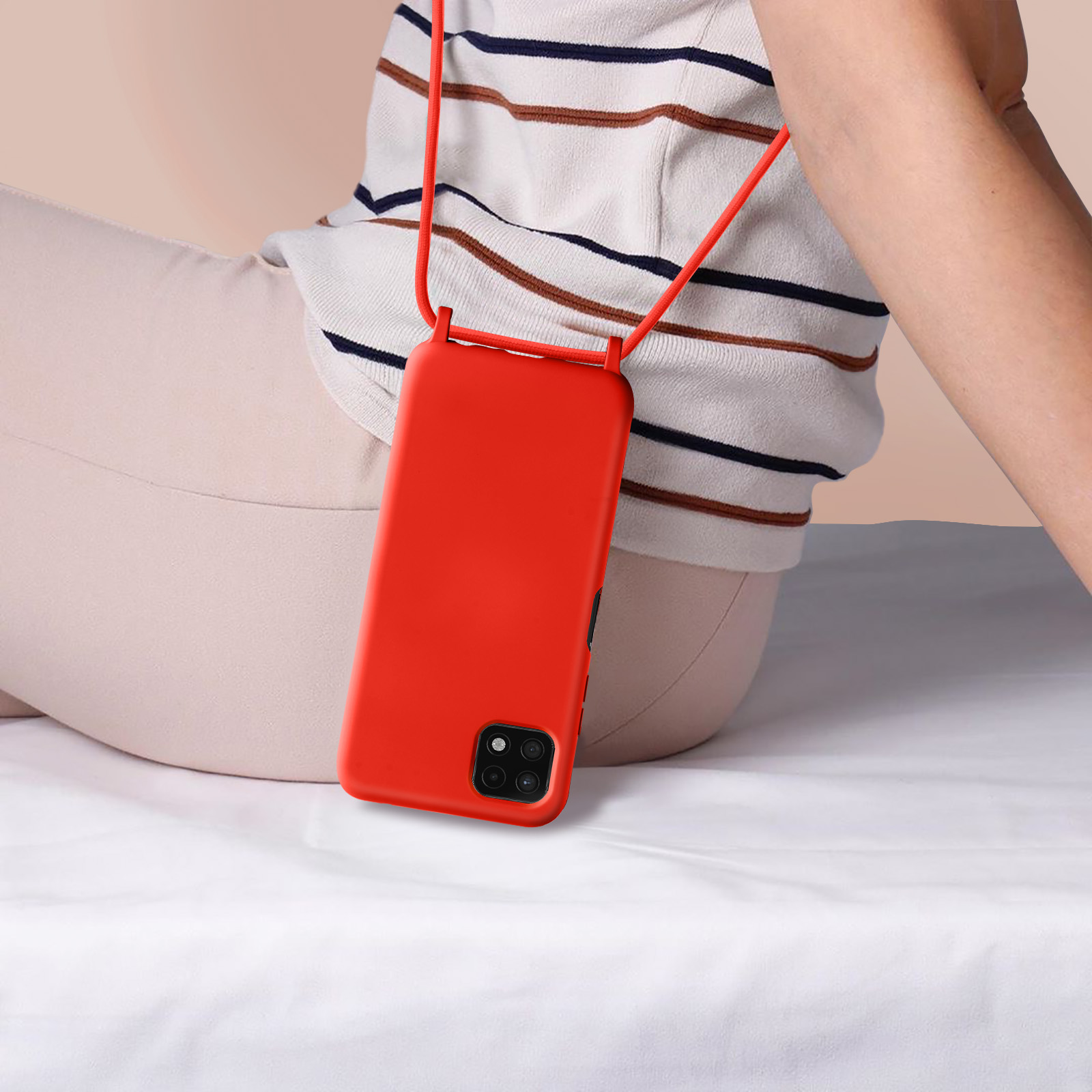 Personne portant une coque de téléphone rouge avec un cordon rouge. Fond blanc.