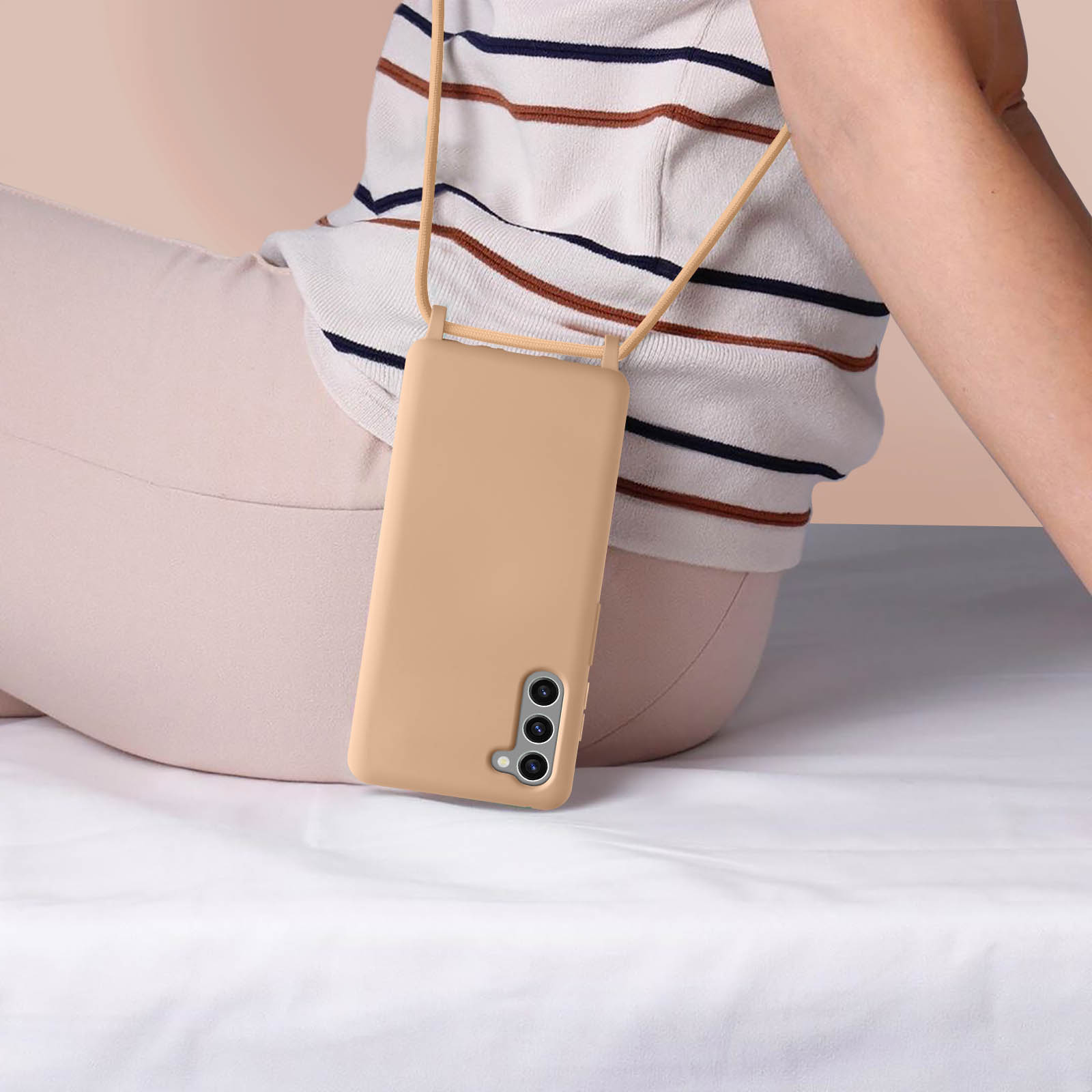 Una persona con una camicia a righe tiene un telefono in una custodia beige con un cinturino.