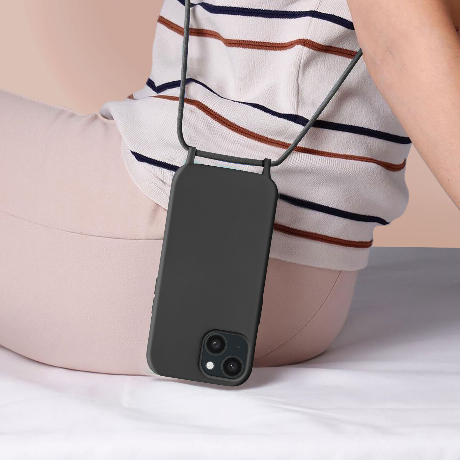 Una persona seduta con una custodia per telefono con cinturino. La custodia è nera e il cinturino è grigio.