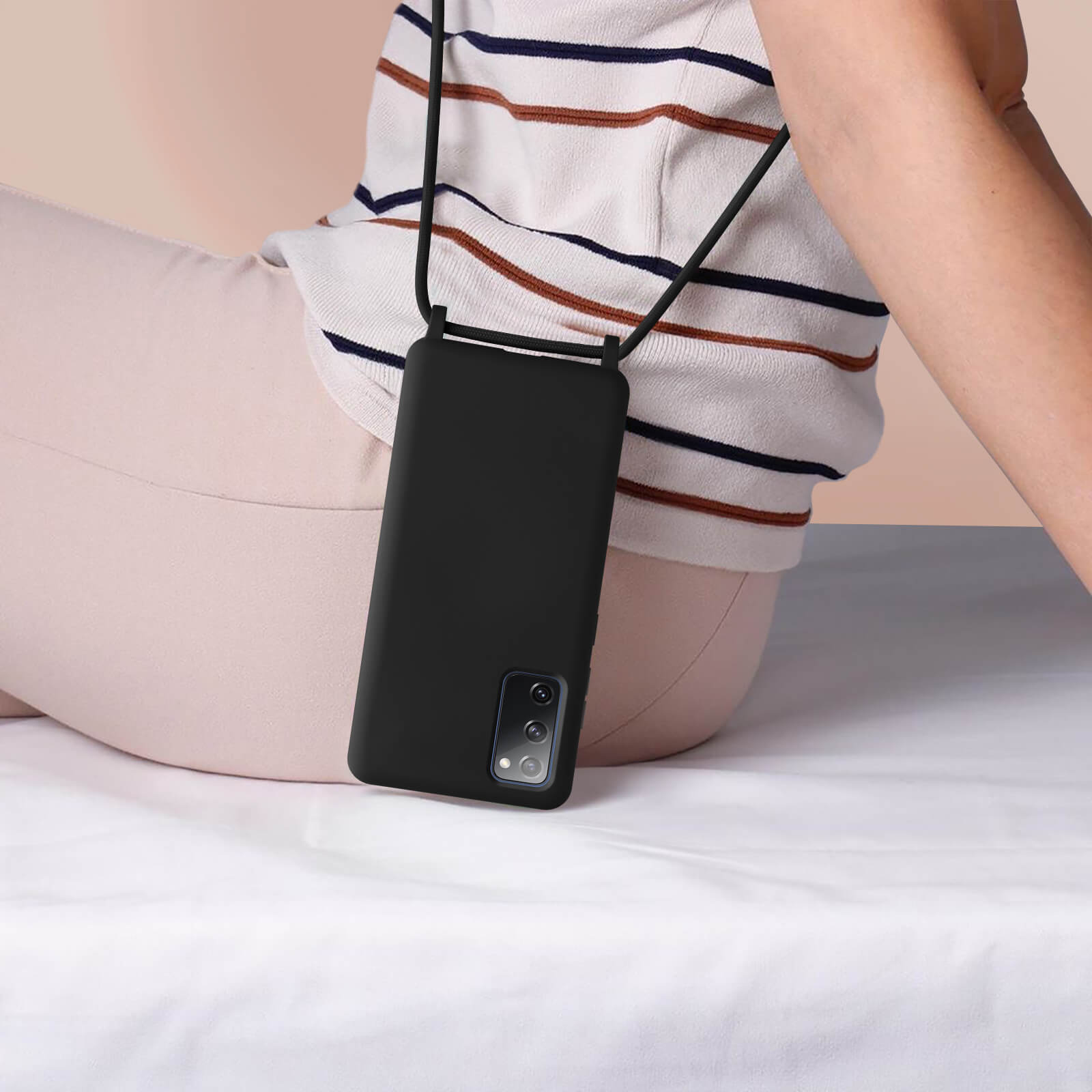Une personne assise avec un téléphone dans une coque noire avec une lanière.