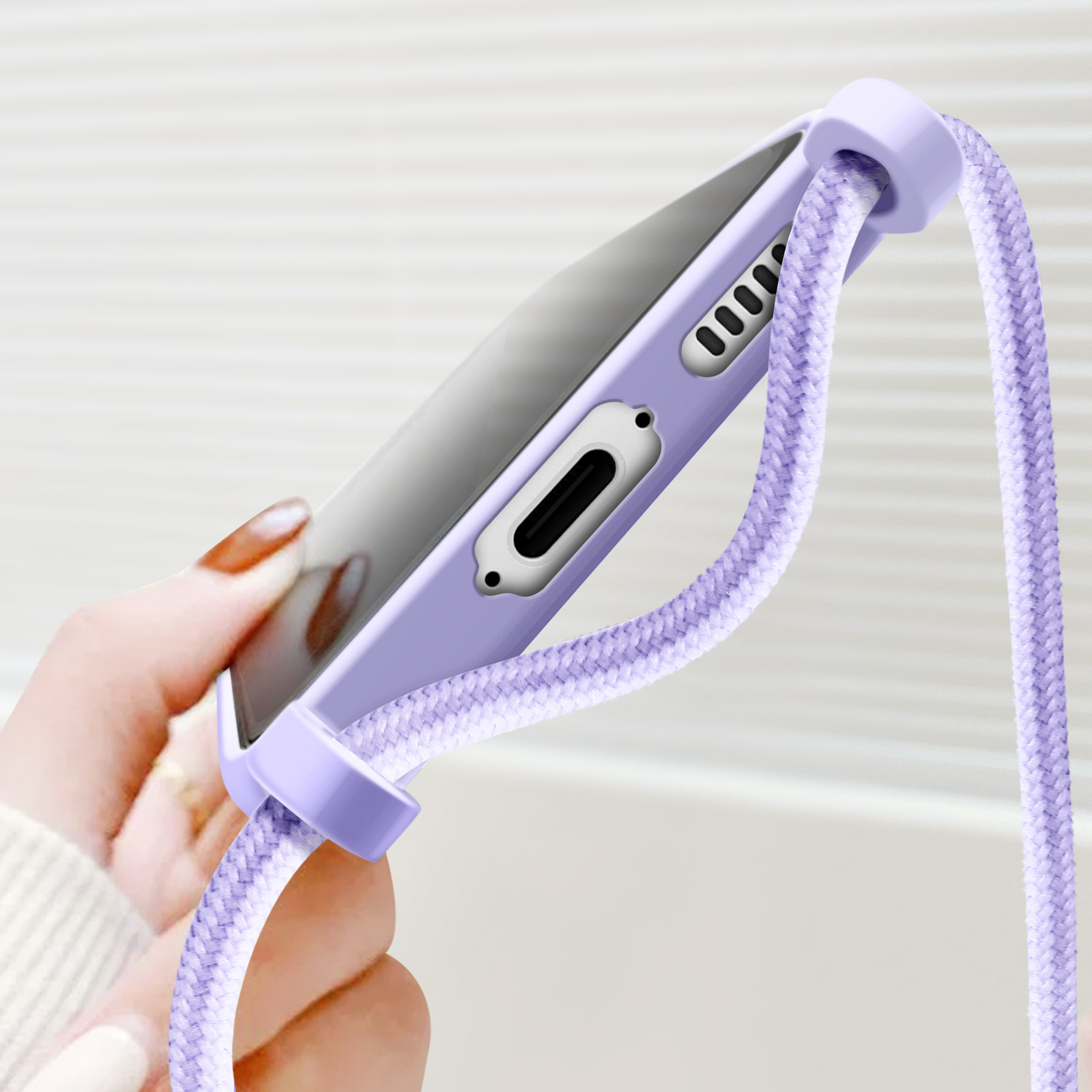 Una mano che tiene una custodia viola per telefono con un cordino, mostrando il lato del telefono.