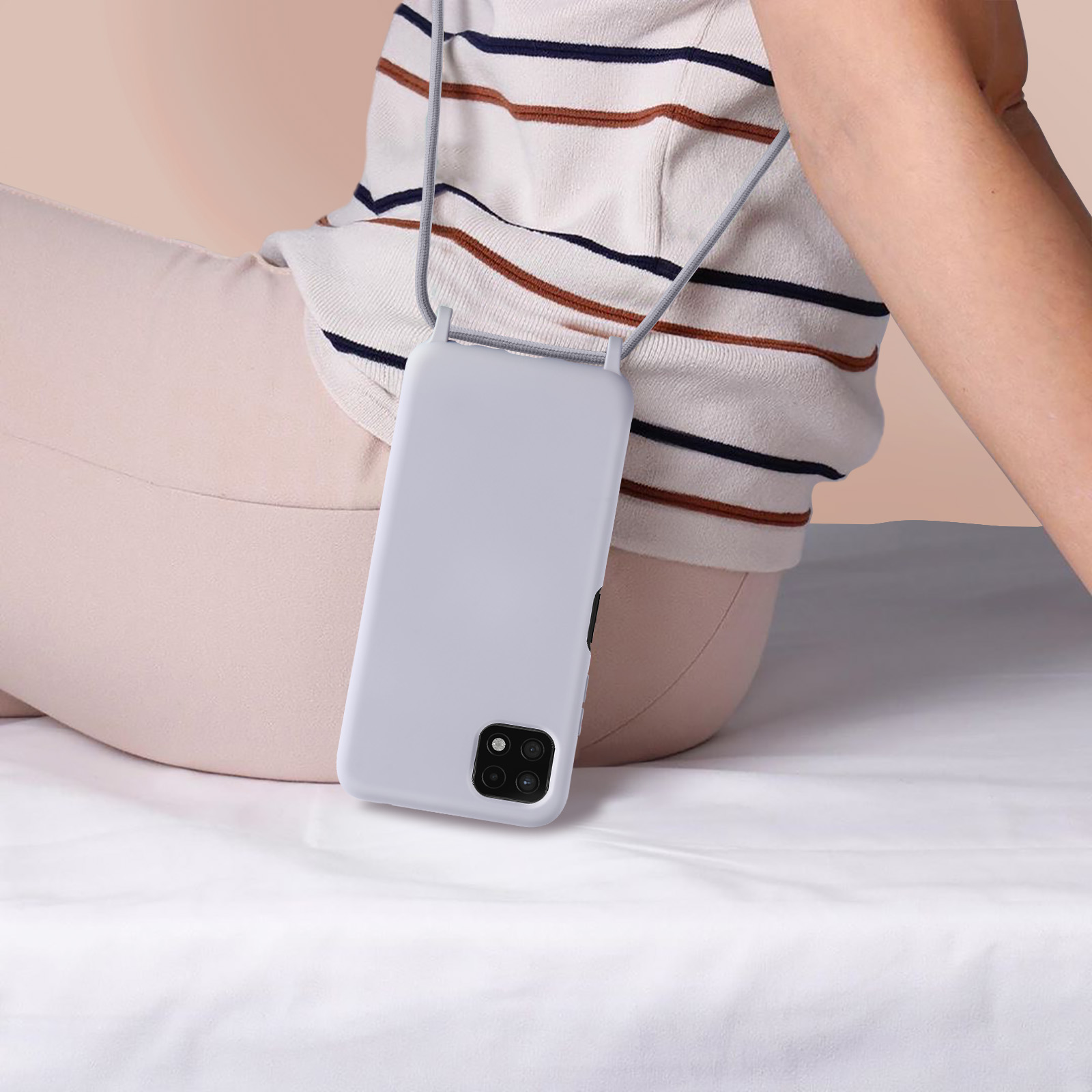 Une personne tenant un téléphone dans un étui gris clair avec une sangle grise.